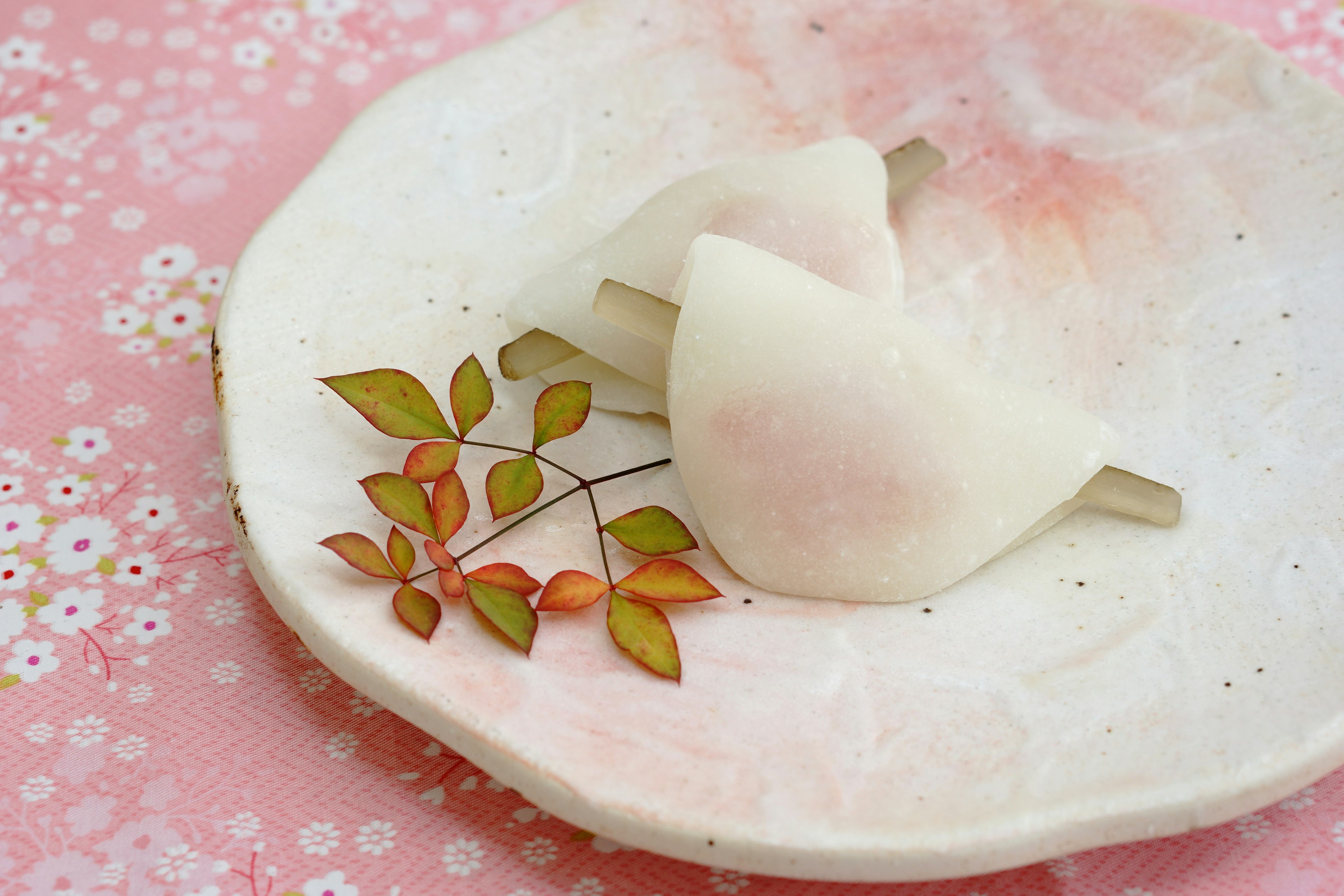 Une assiette avec des douceurs japonaises blanches sur un fond rose