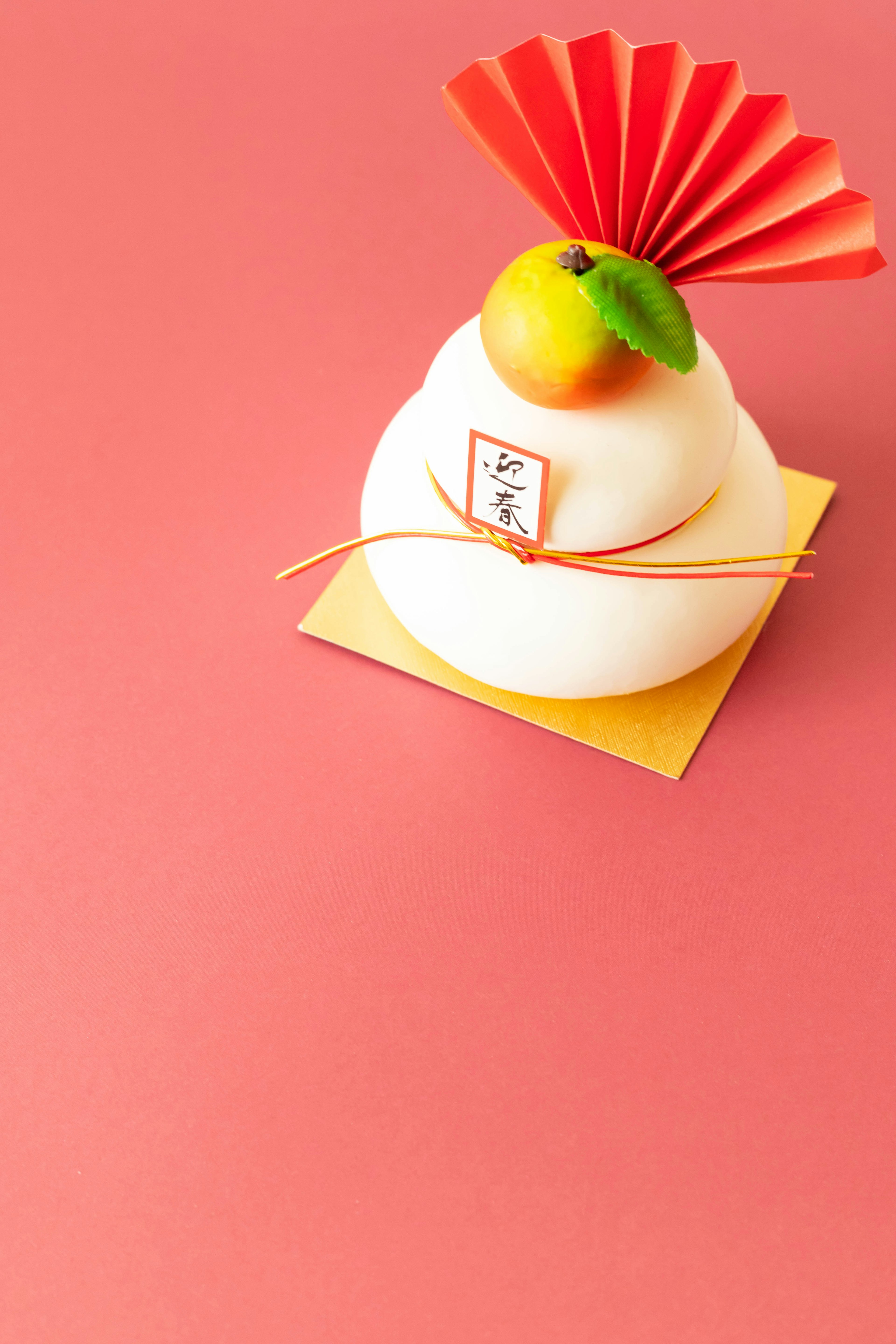 Japanese New Year sweets adorned with a red fan and a mandarin orange