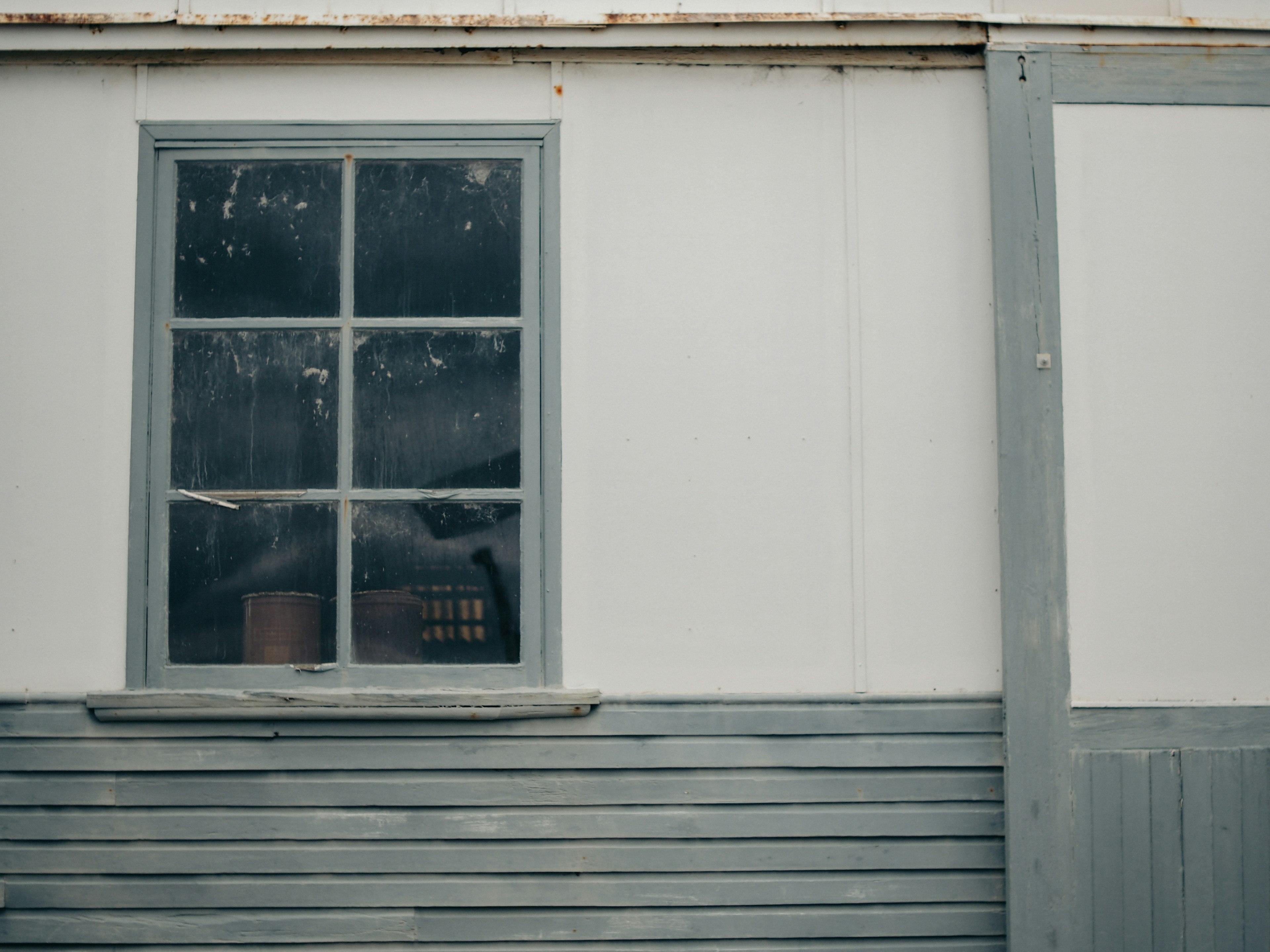 Foto de un marco de ventana gris con un exterior de pared blanca