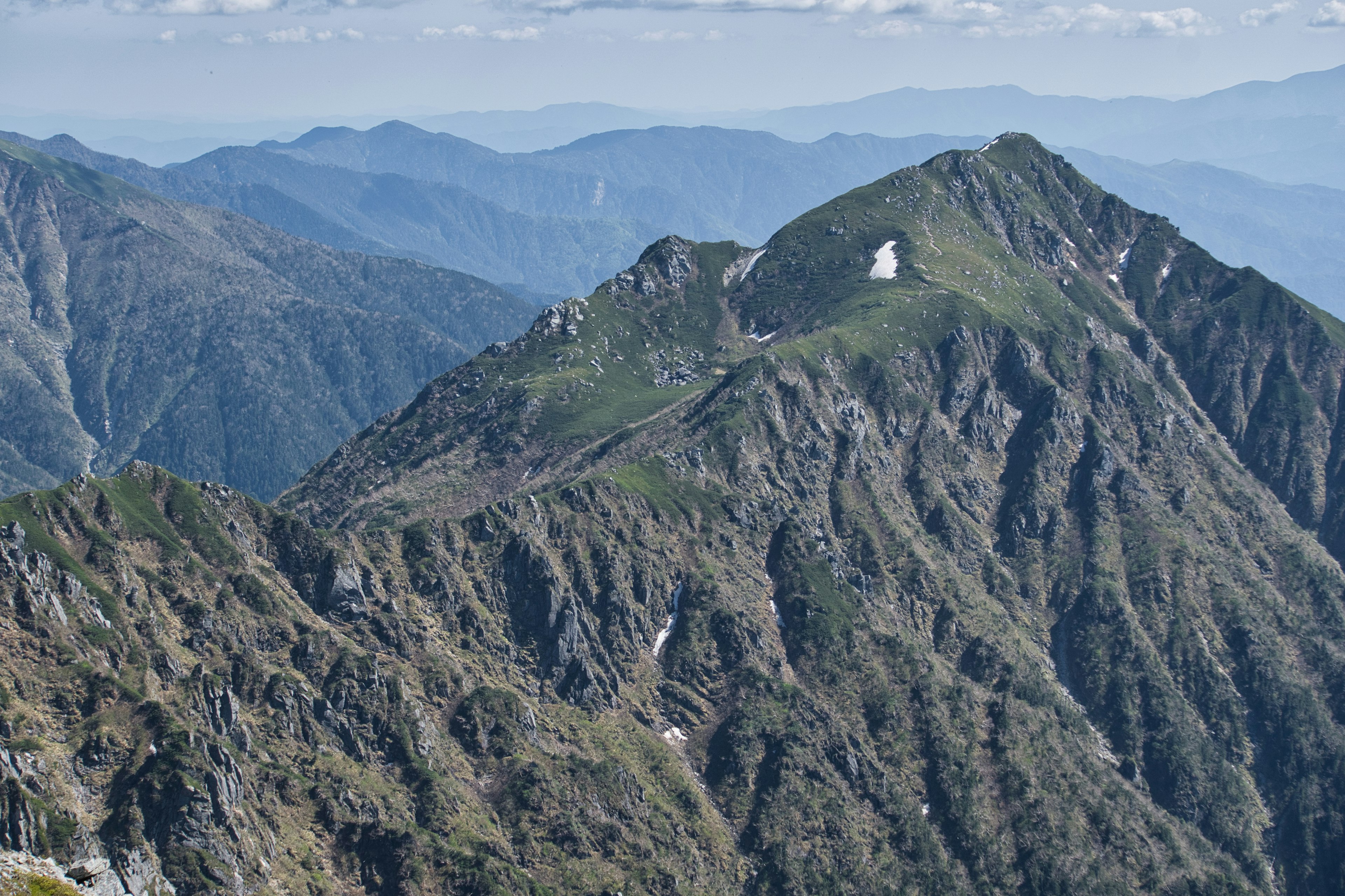 Vista escénica de montañas con picos verdes y laderas rocosas