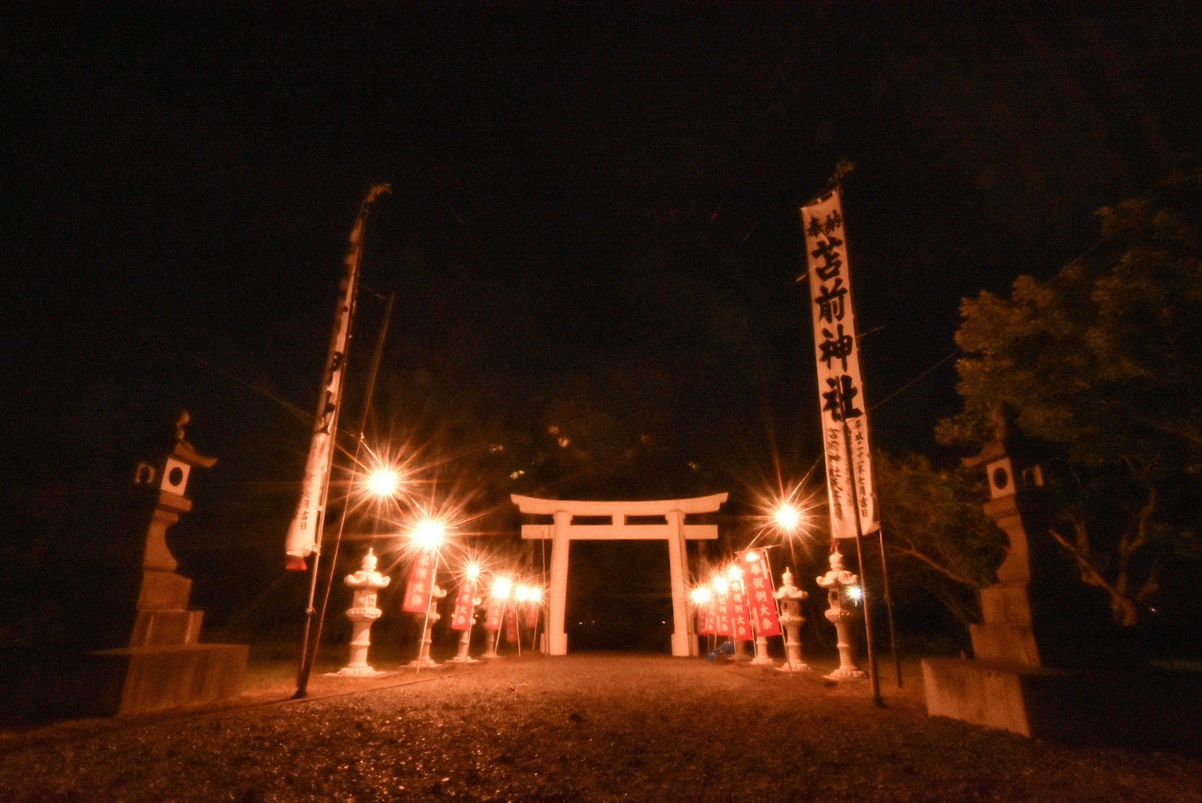 Hermosa vista de un torii y faroles en un santuario de noche