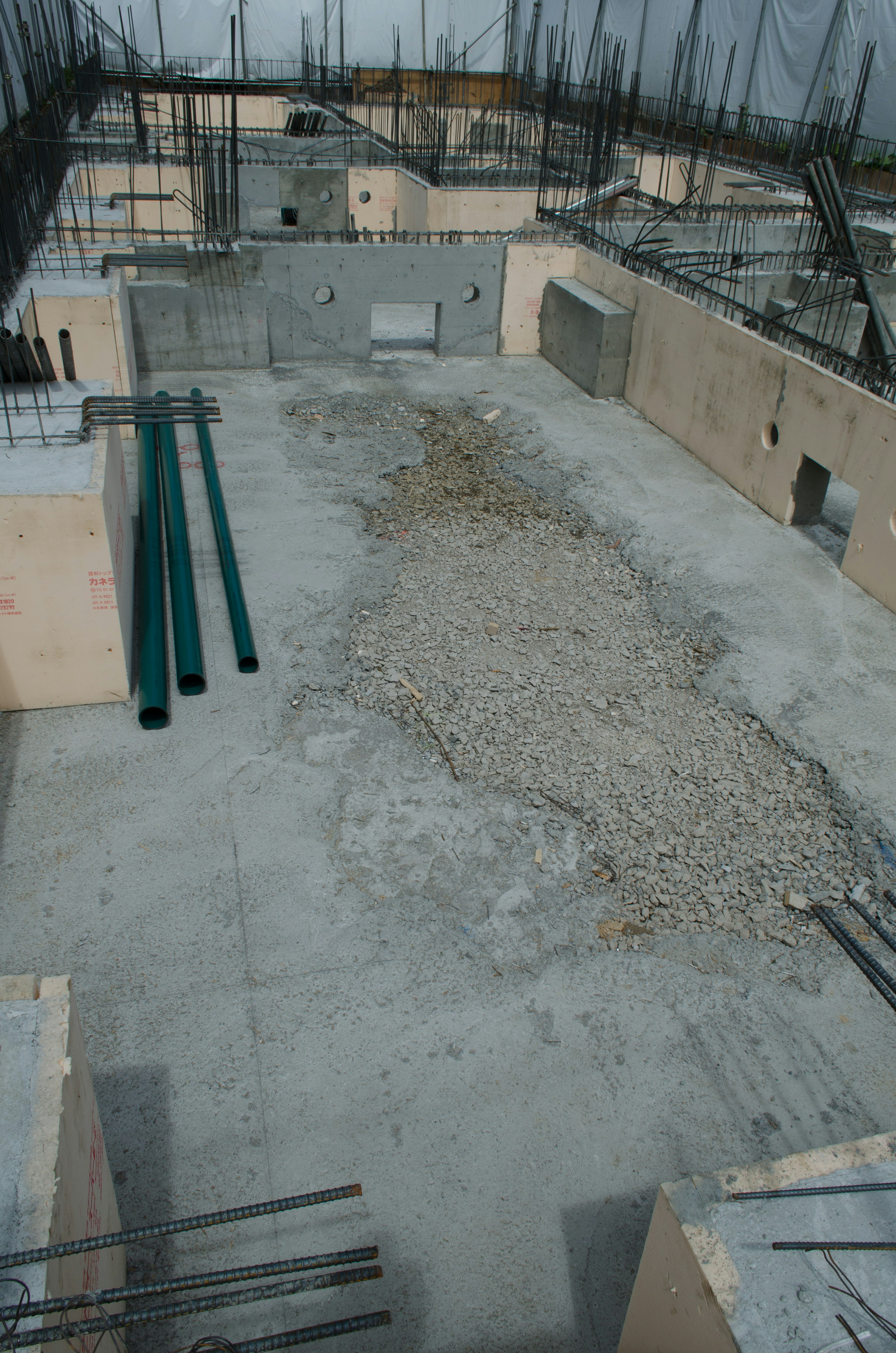 Construction site featuring a concrete floor with exposed rocky area and surrounding walls