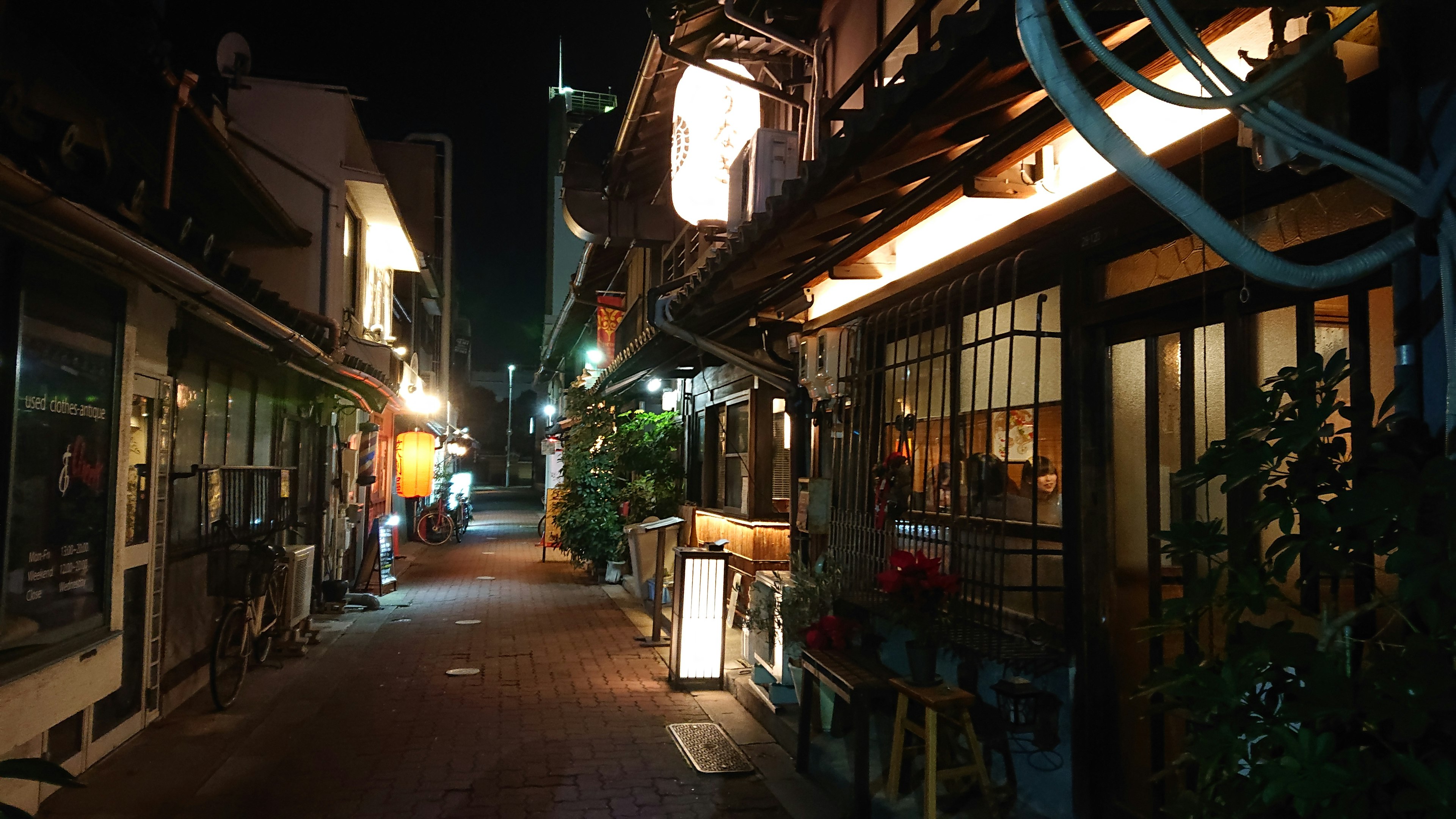 Lorong sempit dengan bangunan tradisional Jepang yang diterangi di malam hari