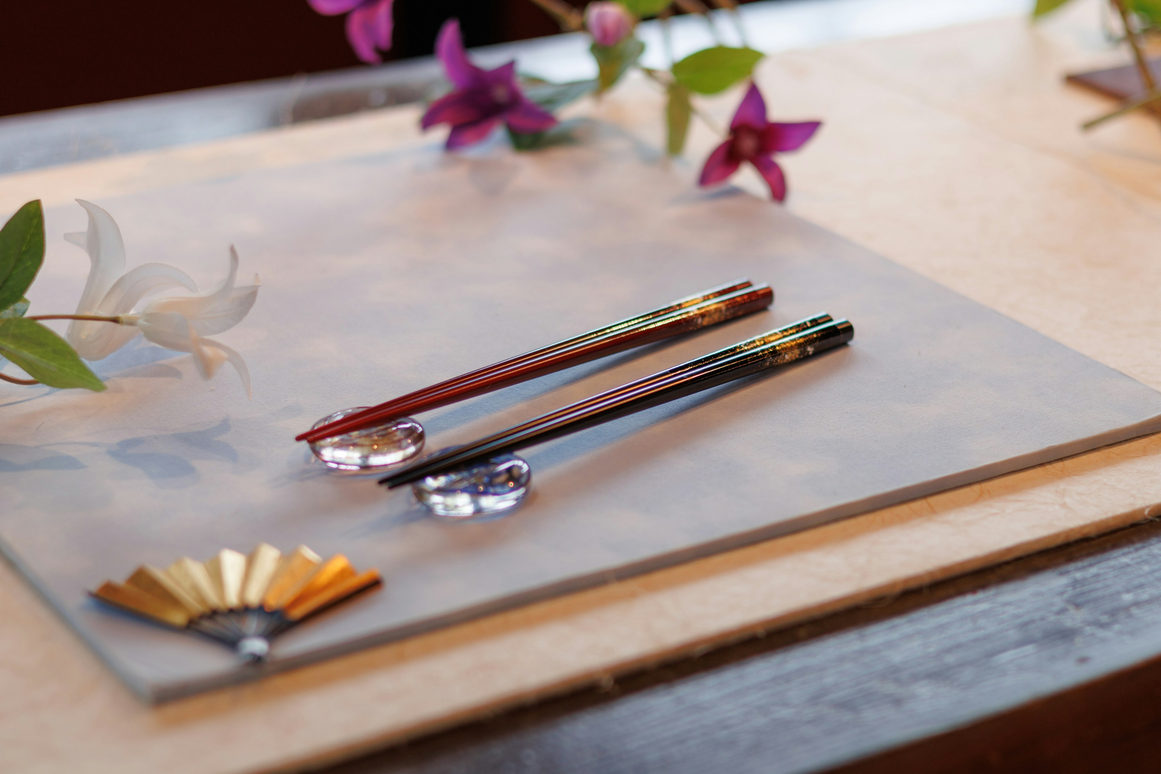 Elegante rote und schwarze Essstäbchen auf einem Tisch mit Blumen