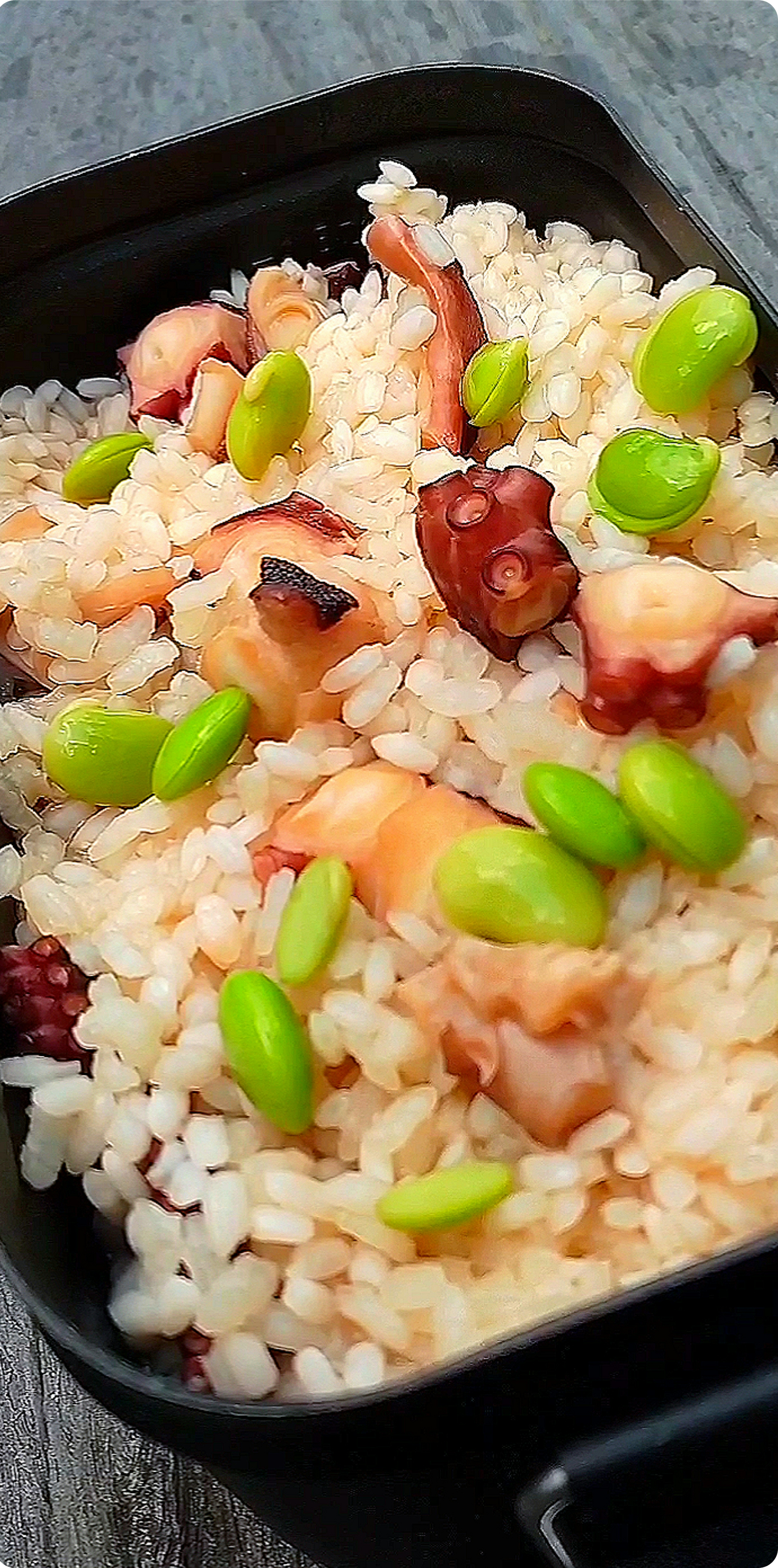 Riz aux poulpes et edamame servi dans un récipient noir