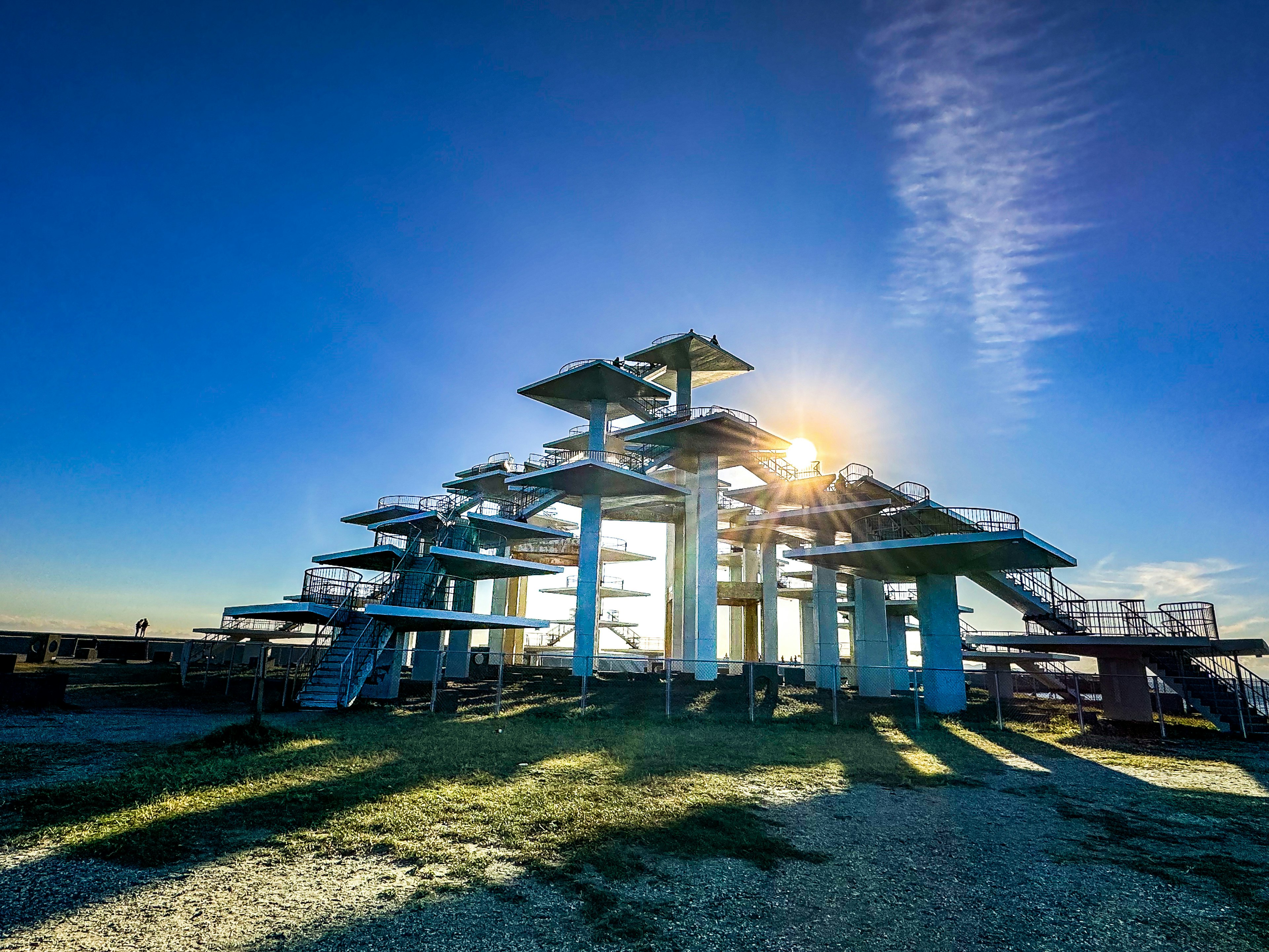 Plataforma de salto multi-nivel bajo un cielo azul claro con largas sombras