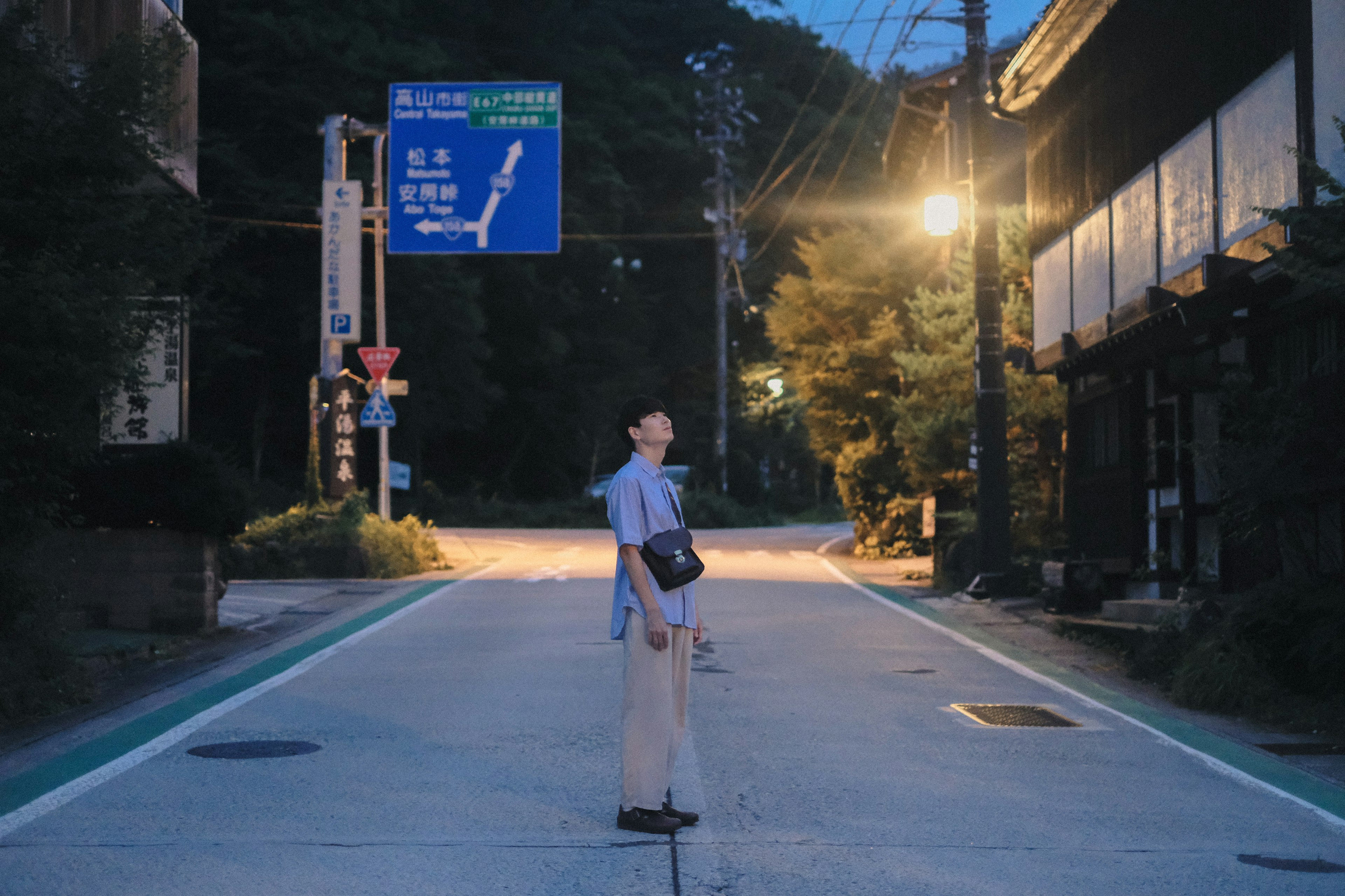 A person standing on a quiet street at night with streetlights illuminating the path