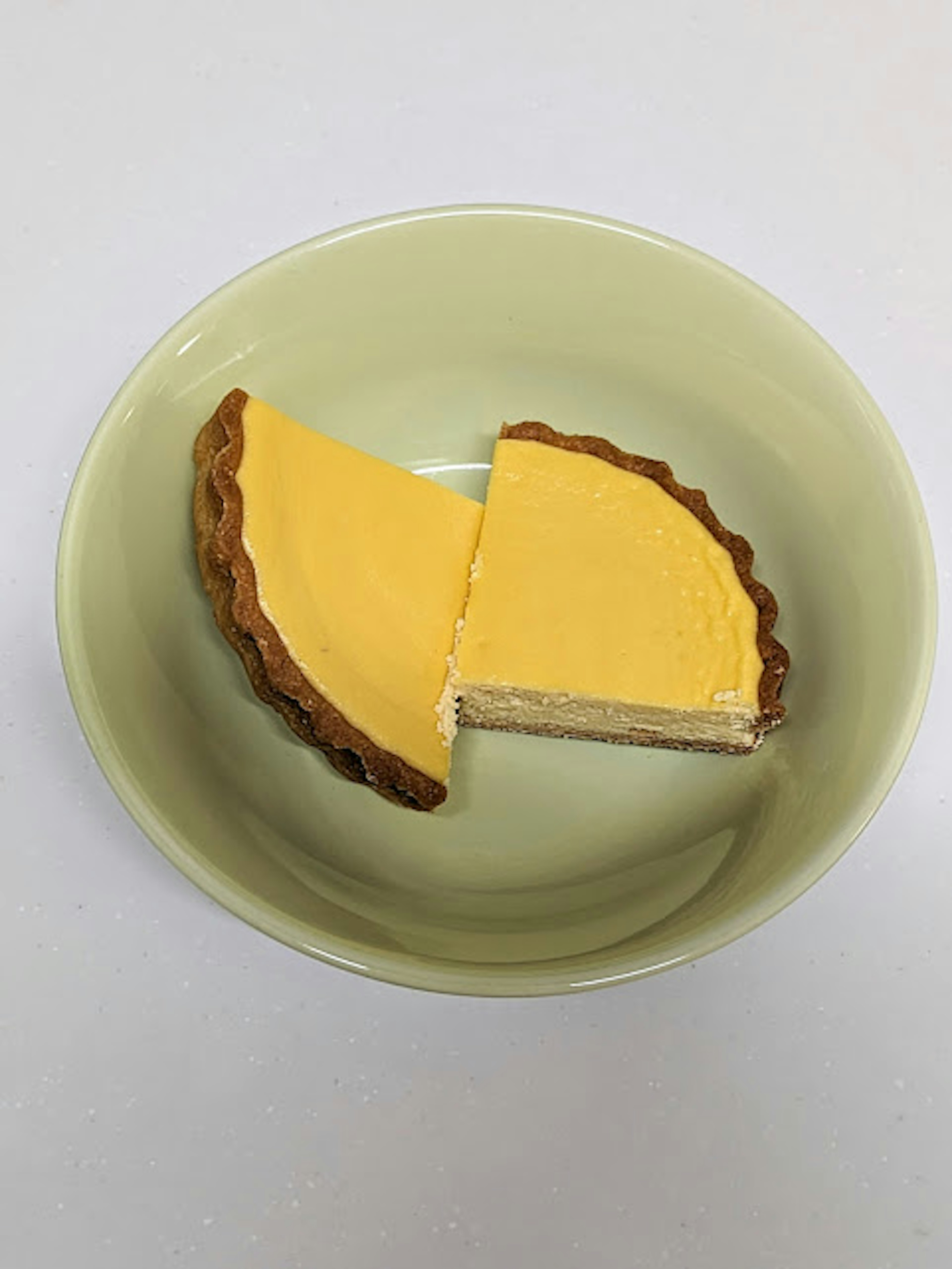 Yellow cream and brown tart cake cut in half on a plate