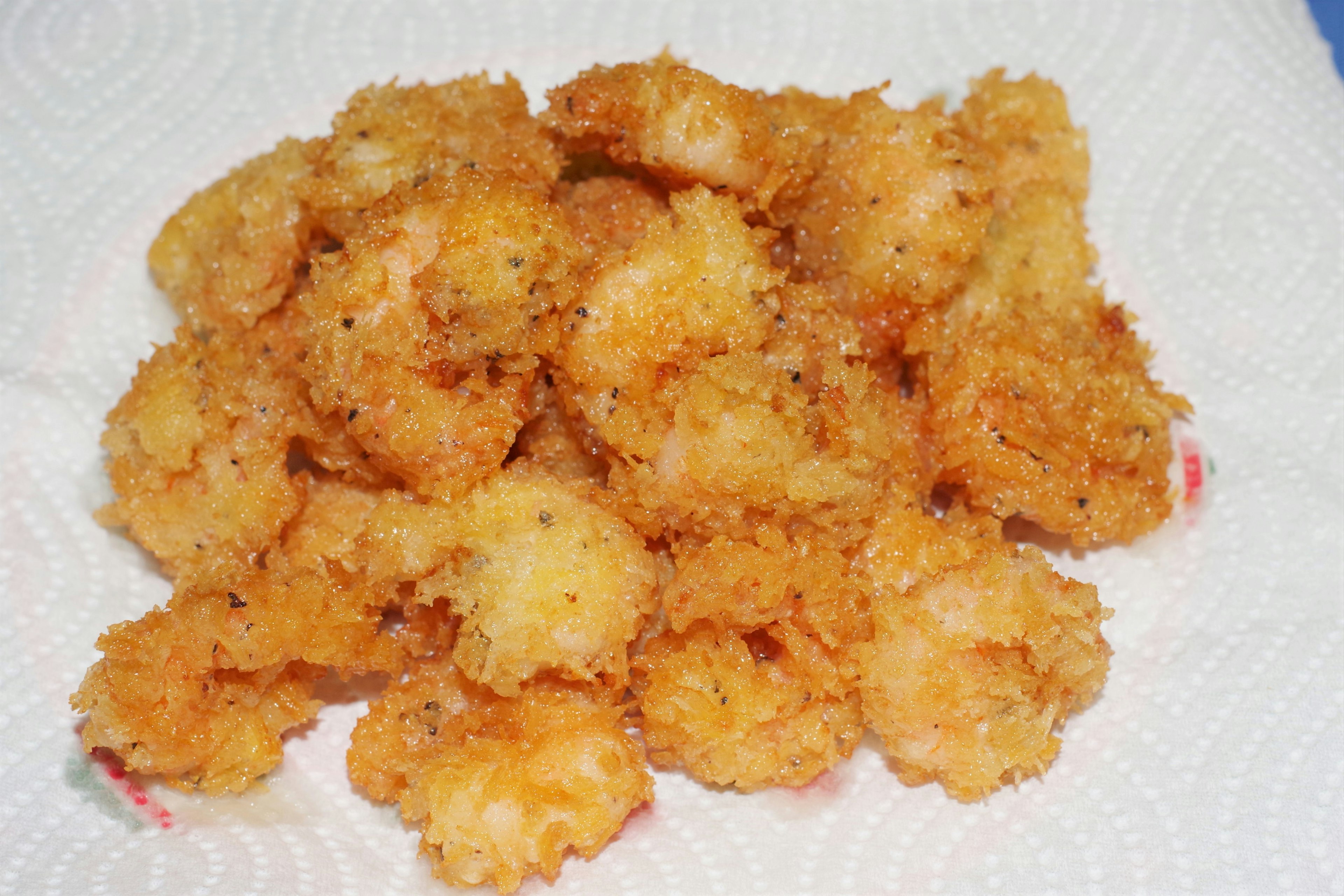 Un montón de camarones fritos sobre una toalla de papel blanca