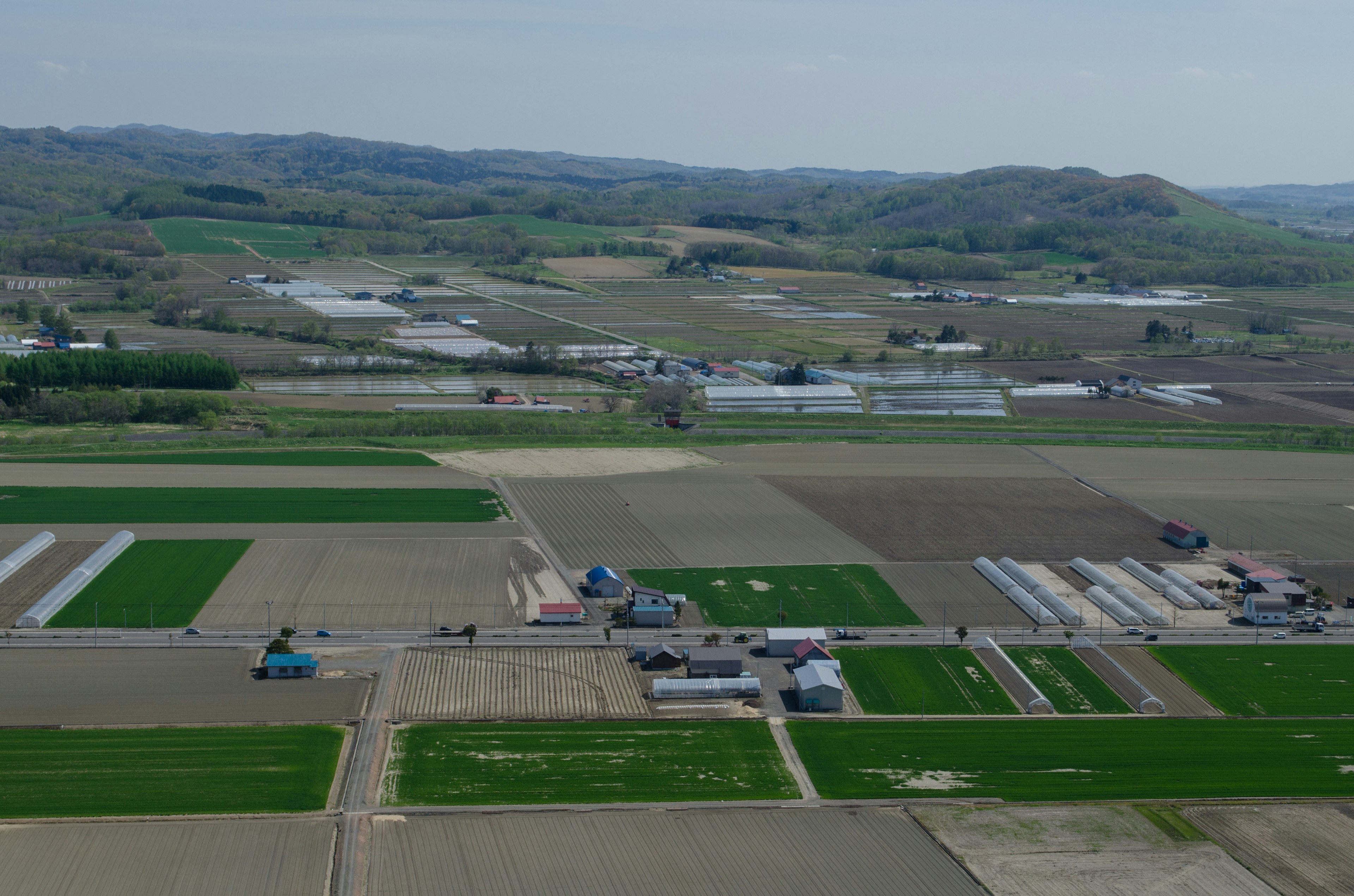 Vista aerea di terreni agricoli verdi con serre e edifici rurali