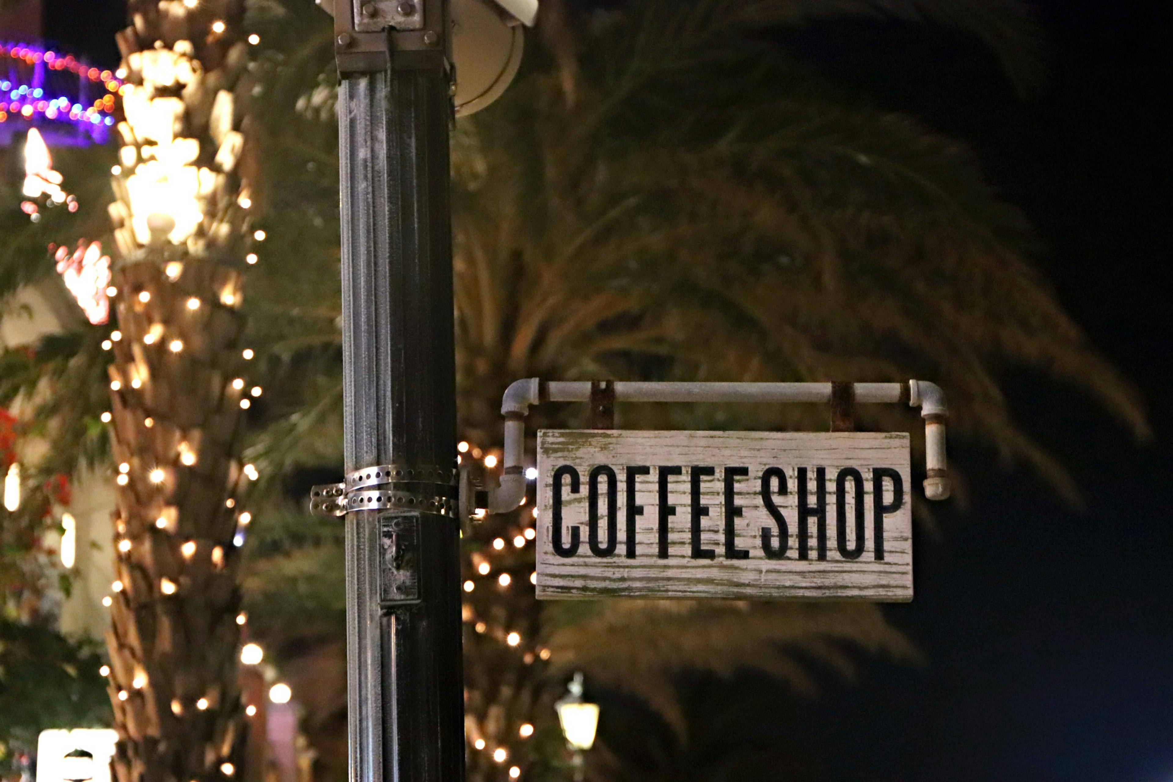 Nachtschild eines Cafés mit Palmen im Hintergrund