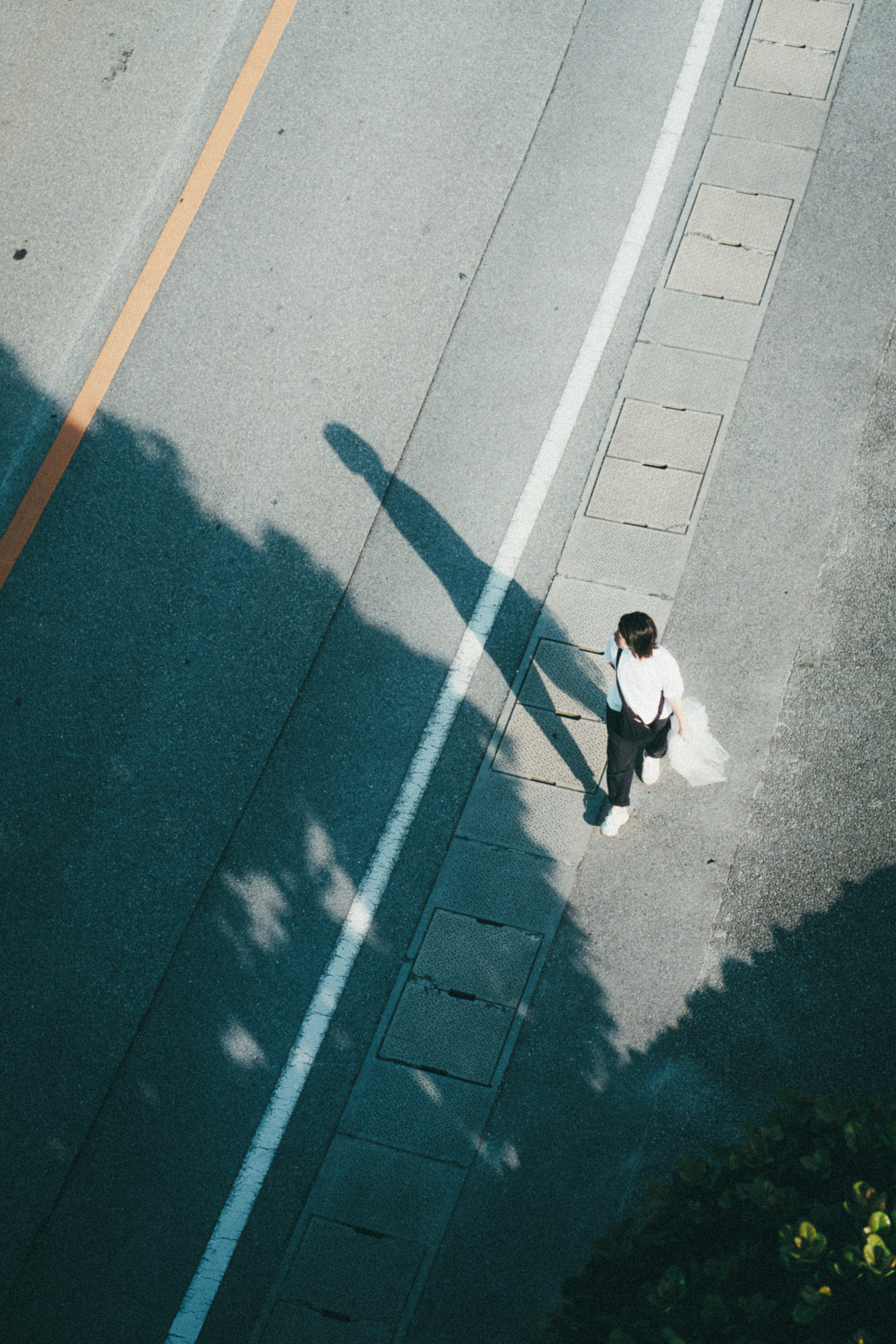 道路を歩く人の上からの視点影が長い