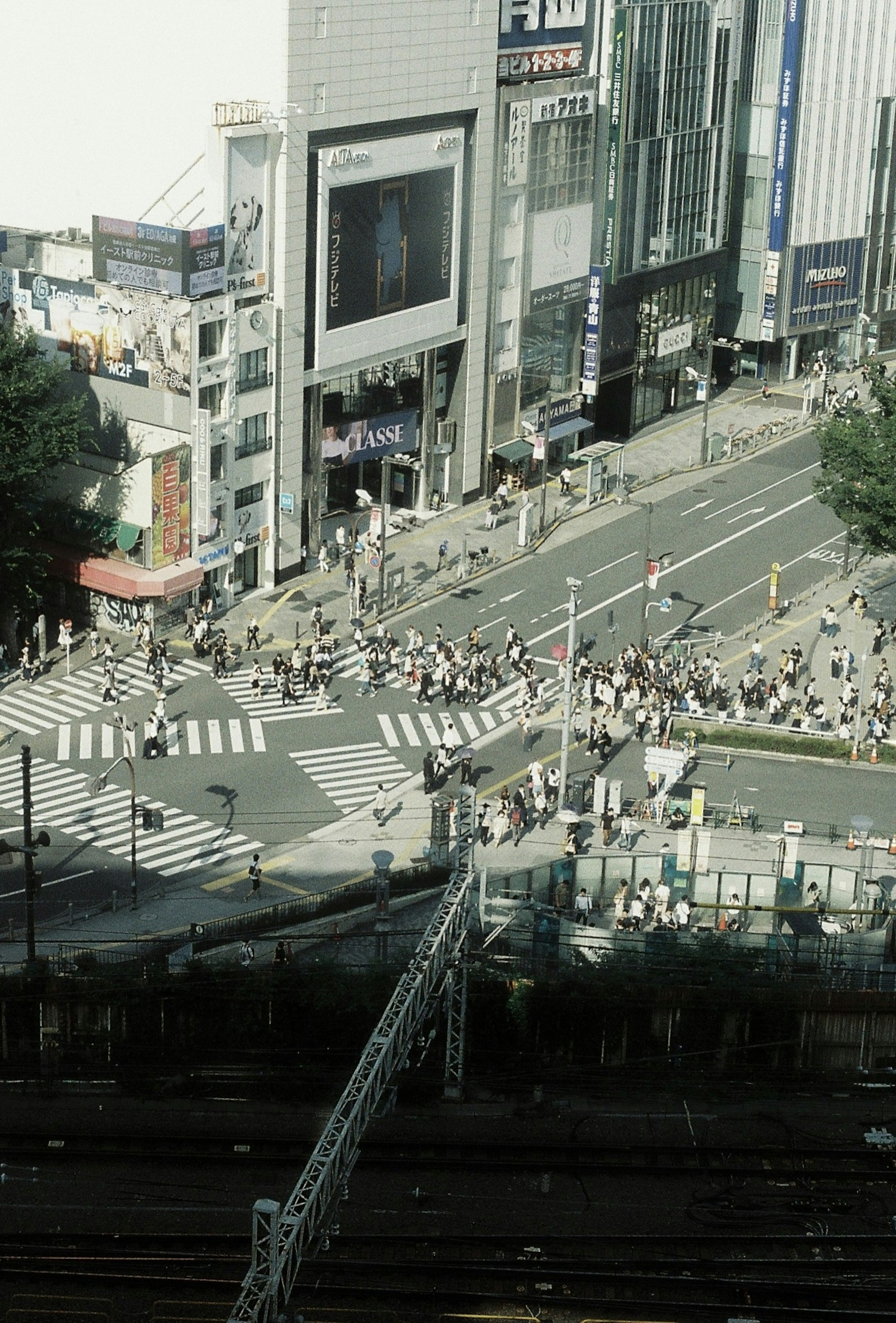 東京の繁華街の交差点の上からの視点で多くの人々が横断歩道を渡っている