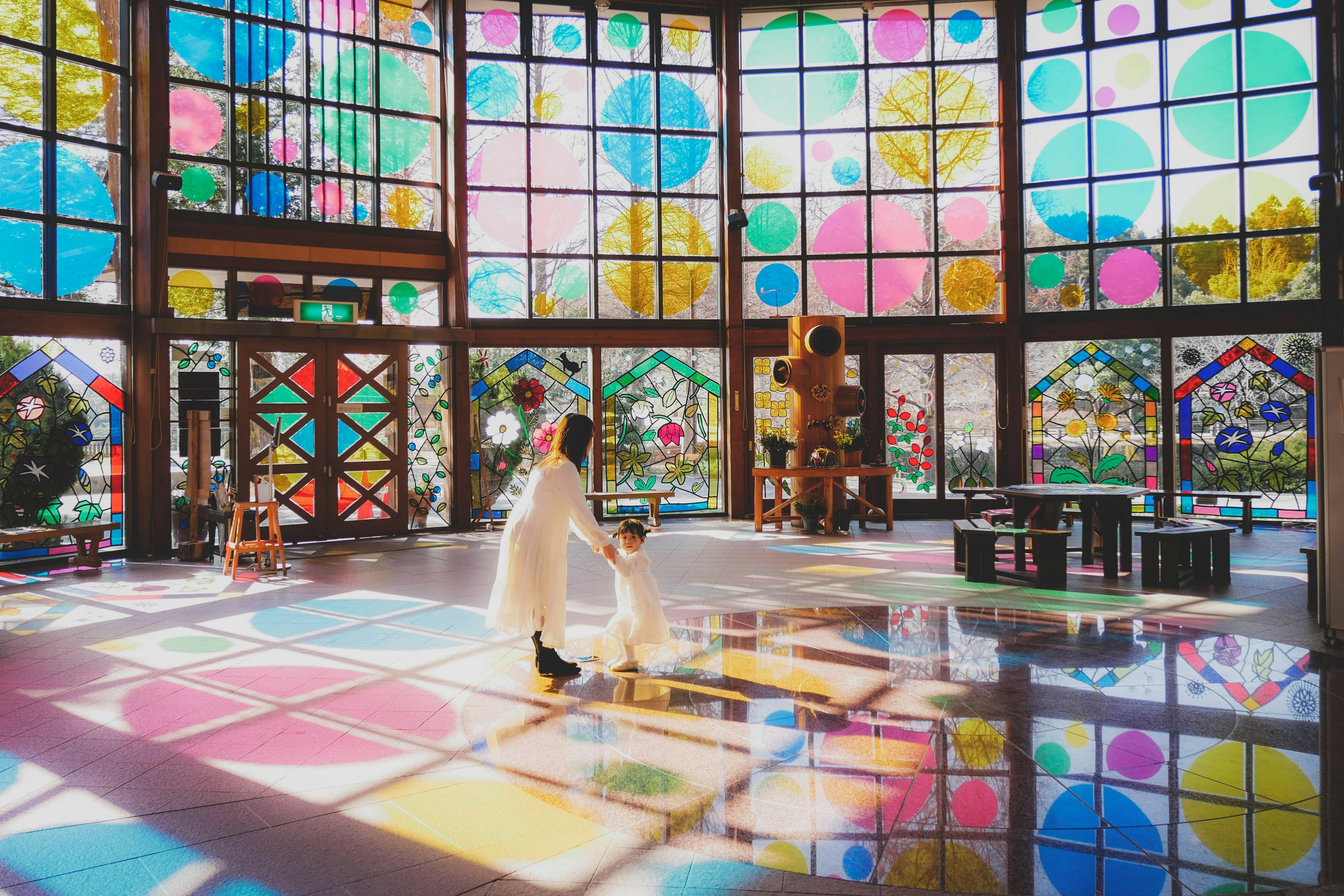 Bright interior with colorful stained glass windows featuring children and adults