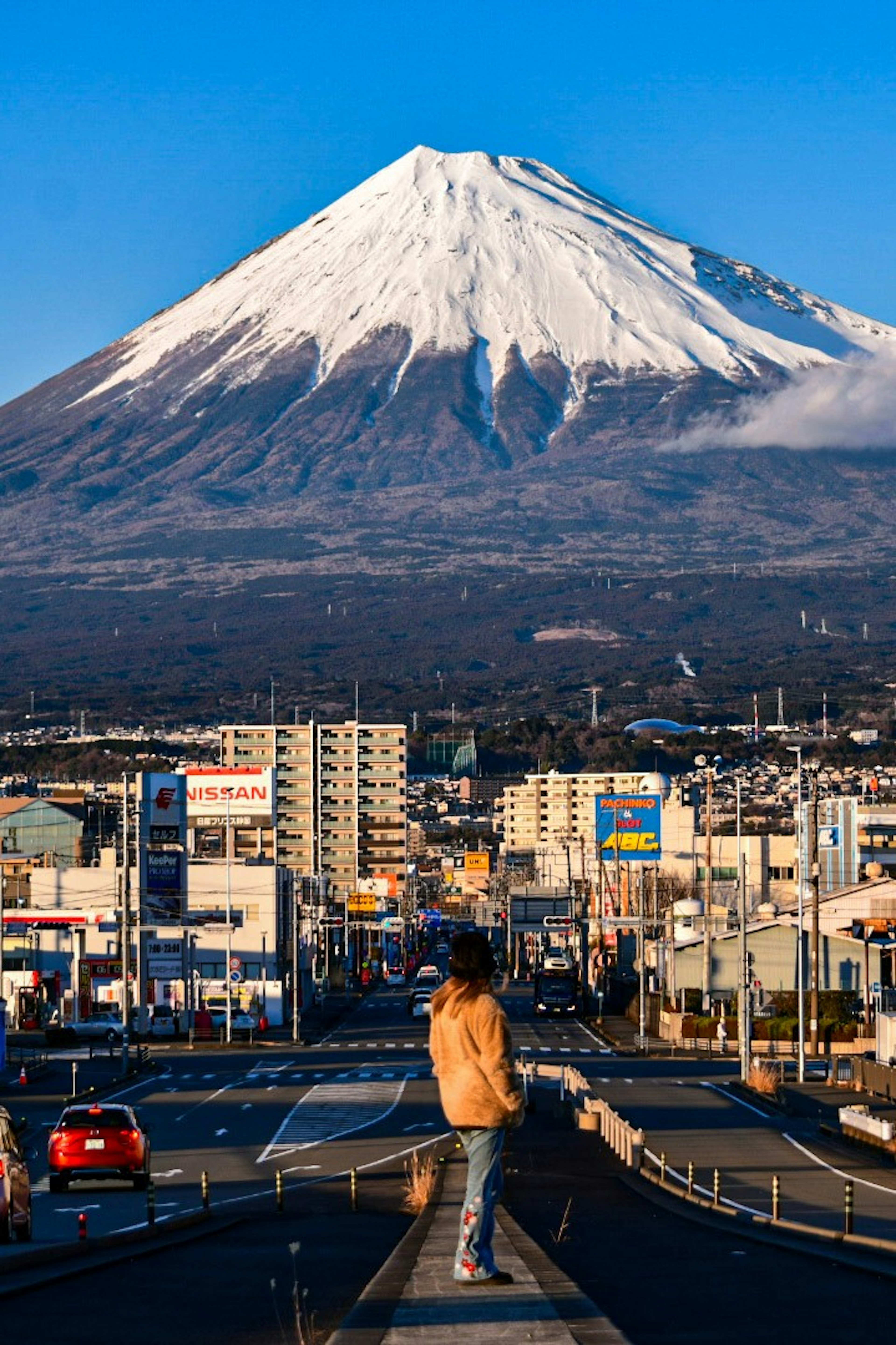 Paisaje urbano con el Monte Fuji al fondo y una persona en la carretera