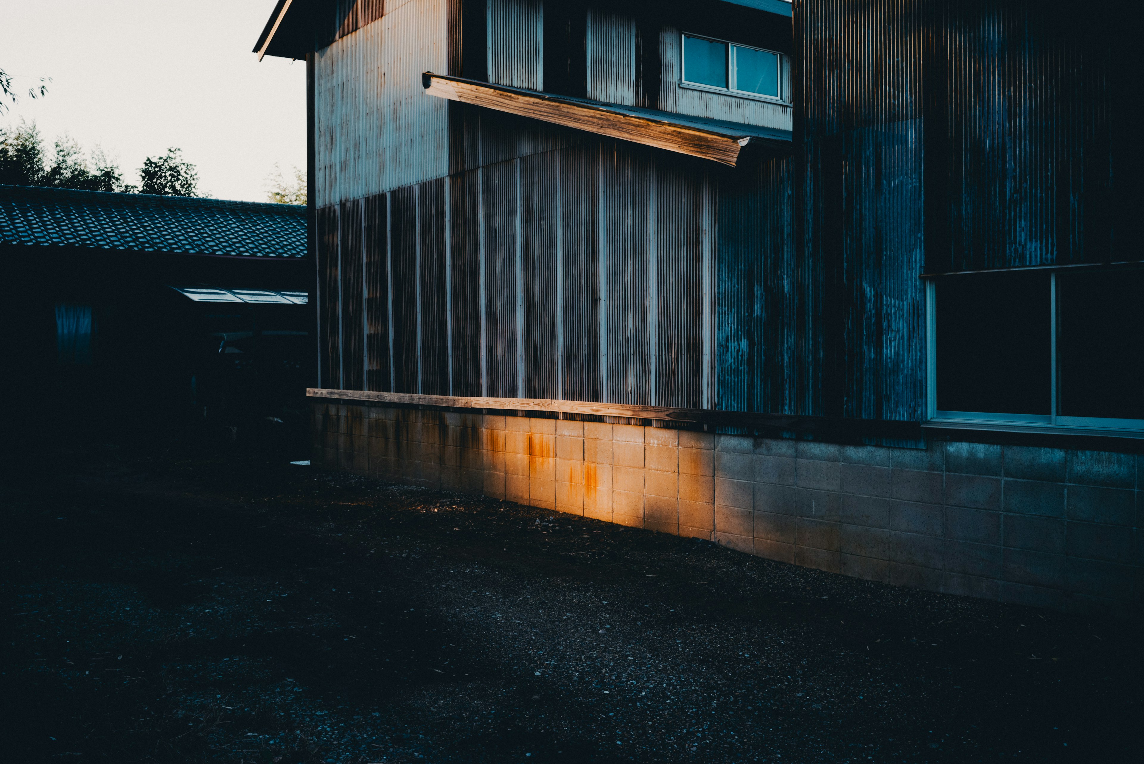 Exterior of an old wooden building at dusk with shadows