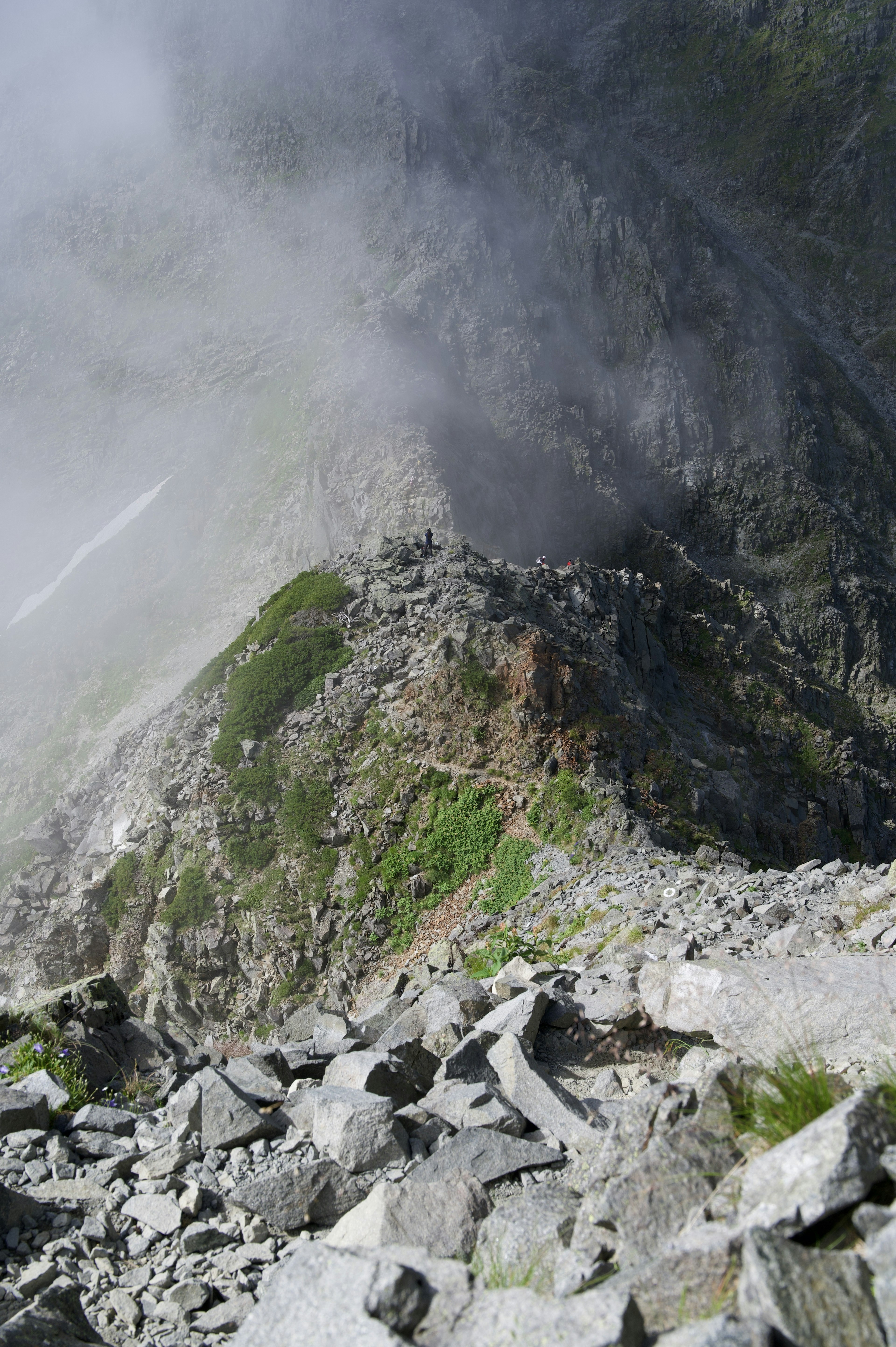 Mountain landscape enveloped in mist with rocky terrain and green grass