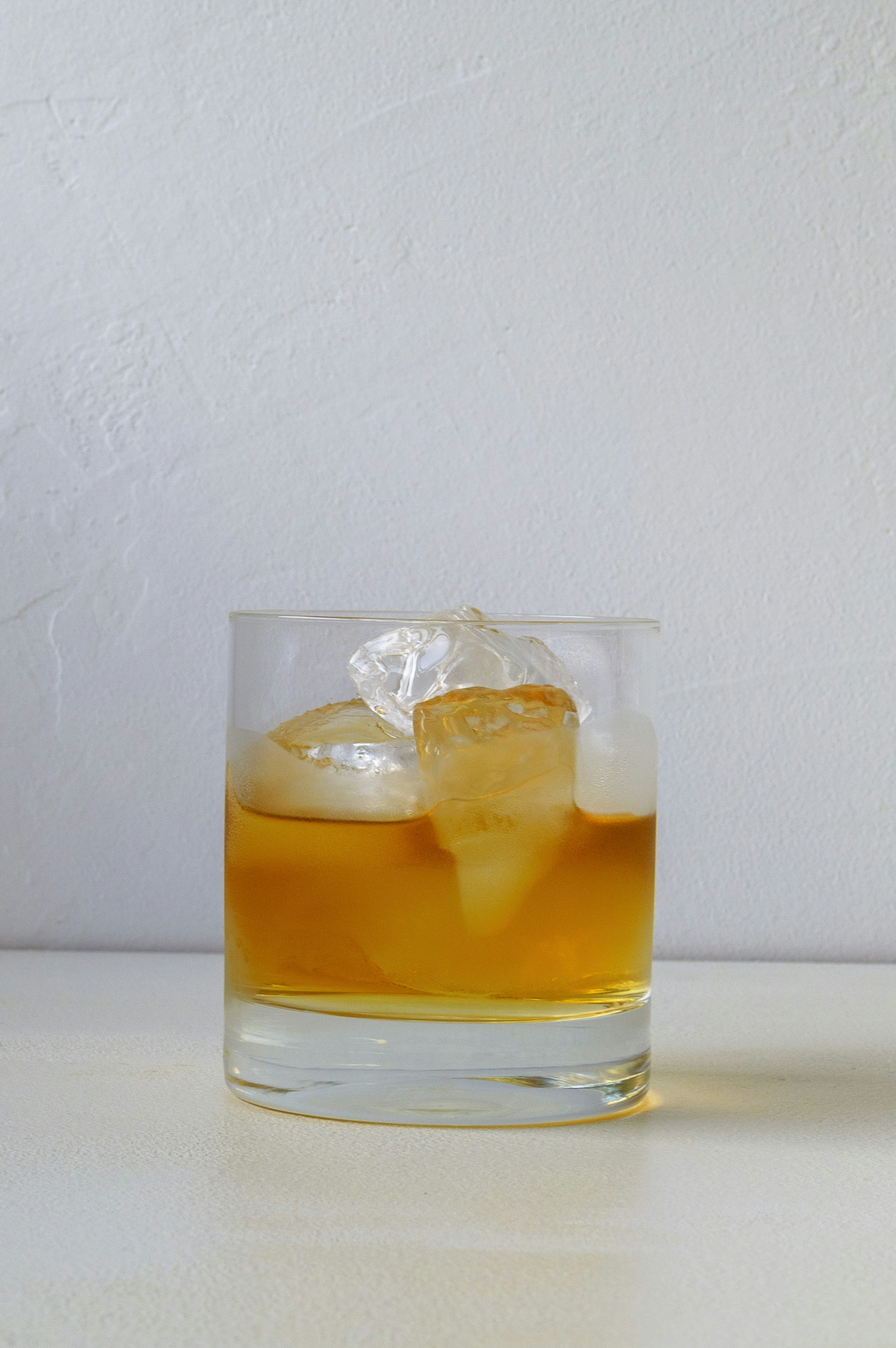 Un vaso de whisky con cubos de hielo sobre un fondo blanco