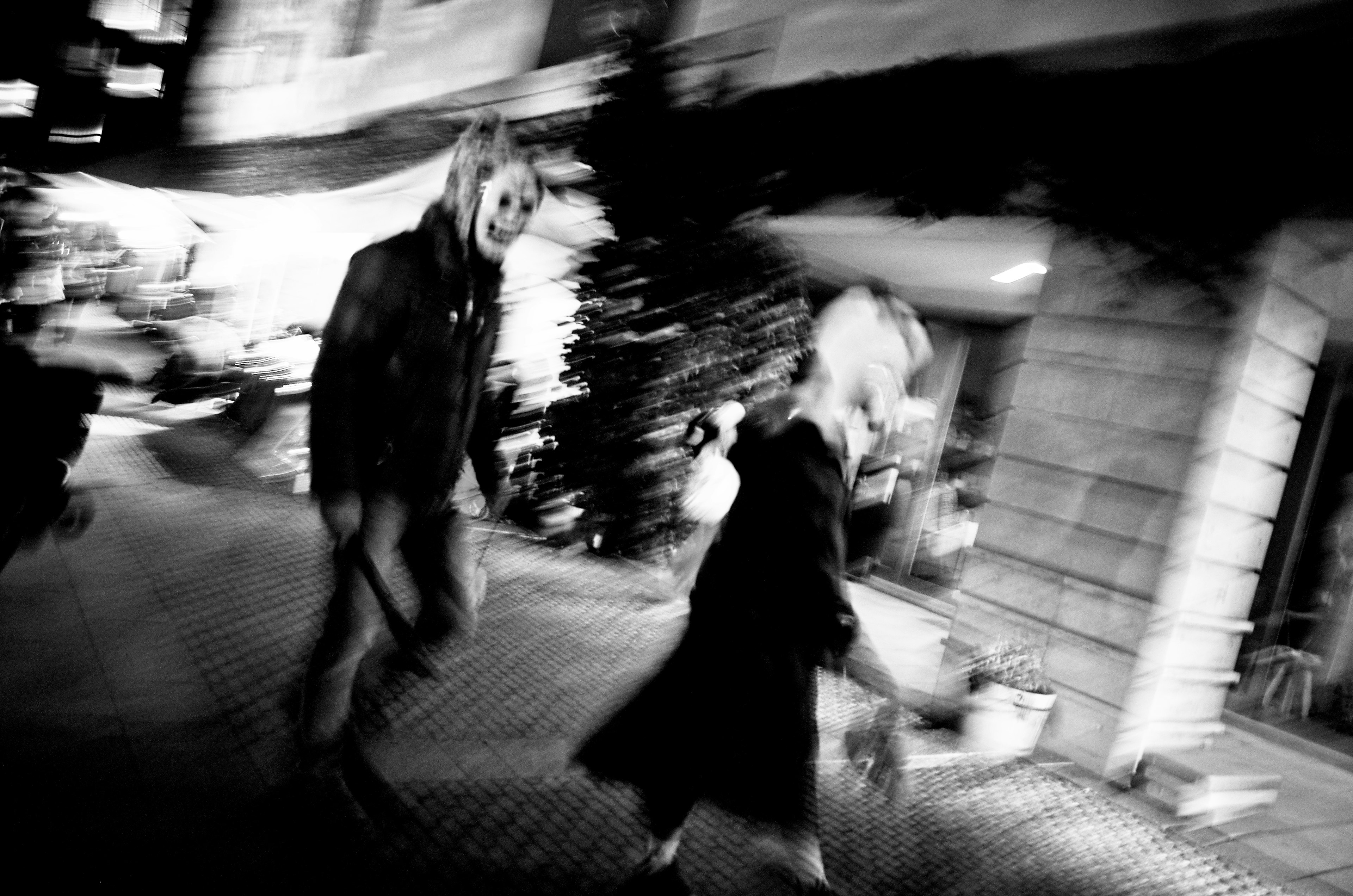 Photo en noir et blanc de deux silhouettes marchant dans la rue avec un flou de mouvement