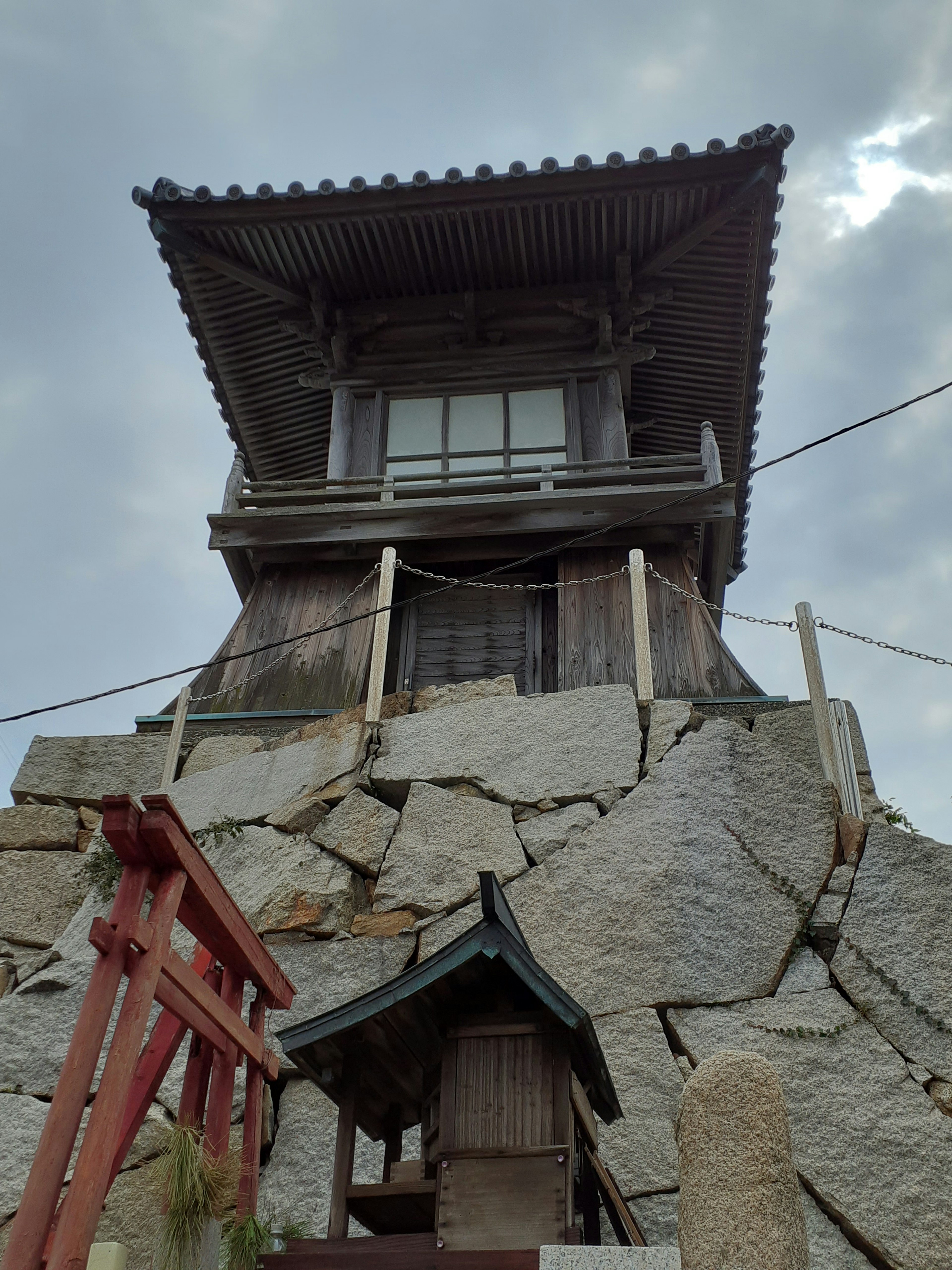 Traditional Japanese building on a rocky foundation with a small shrine