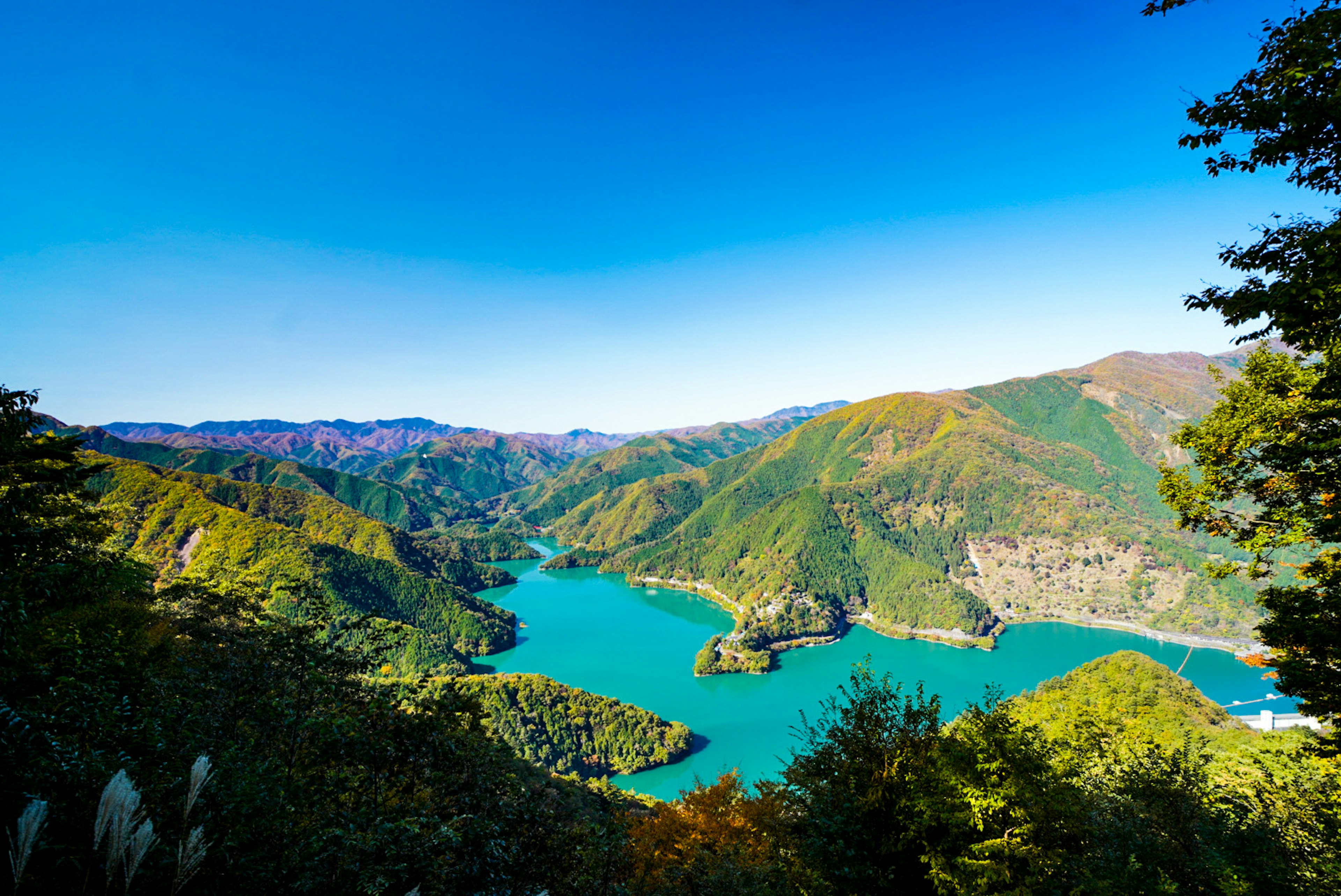 Pemandangan indah pegunungan dan danau turquoise di bawah langit biru yang cerah