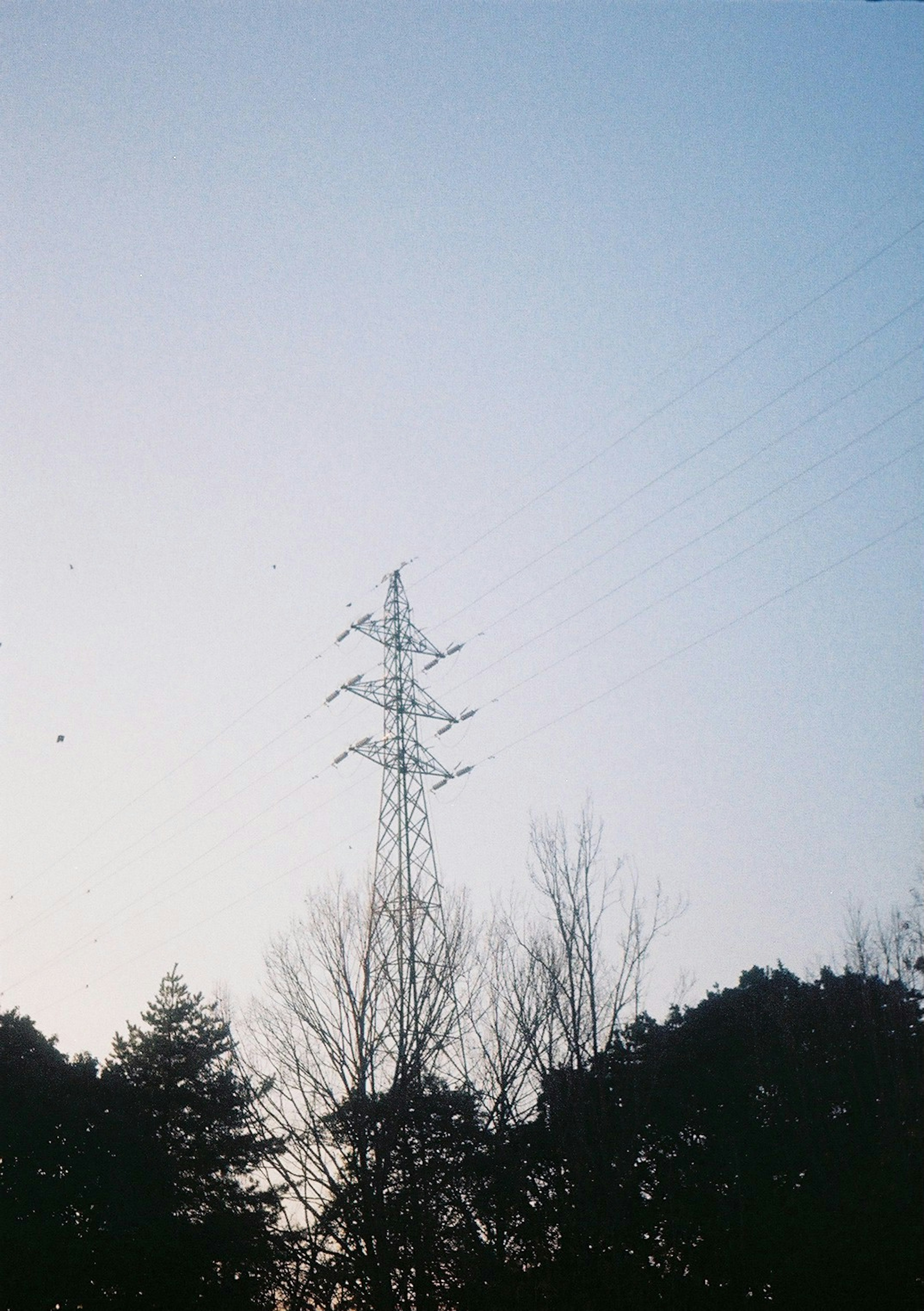 Silhouette of a power tower against a lightening sky