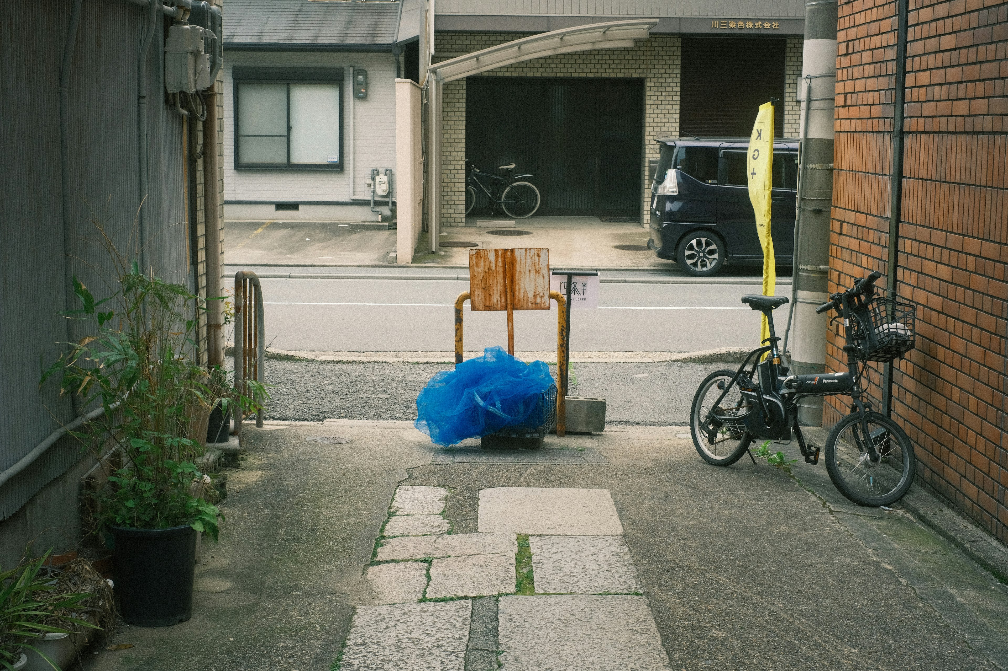 狭い通りに面した小道の景色 自転車と青いビニール袋 木製の椅子が置かれている