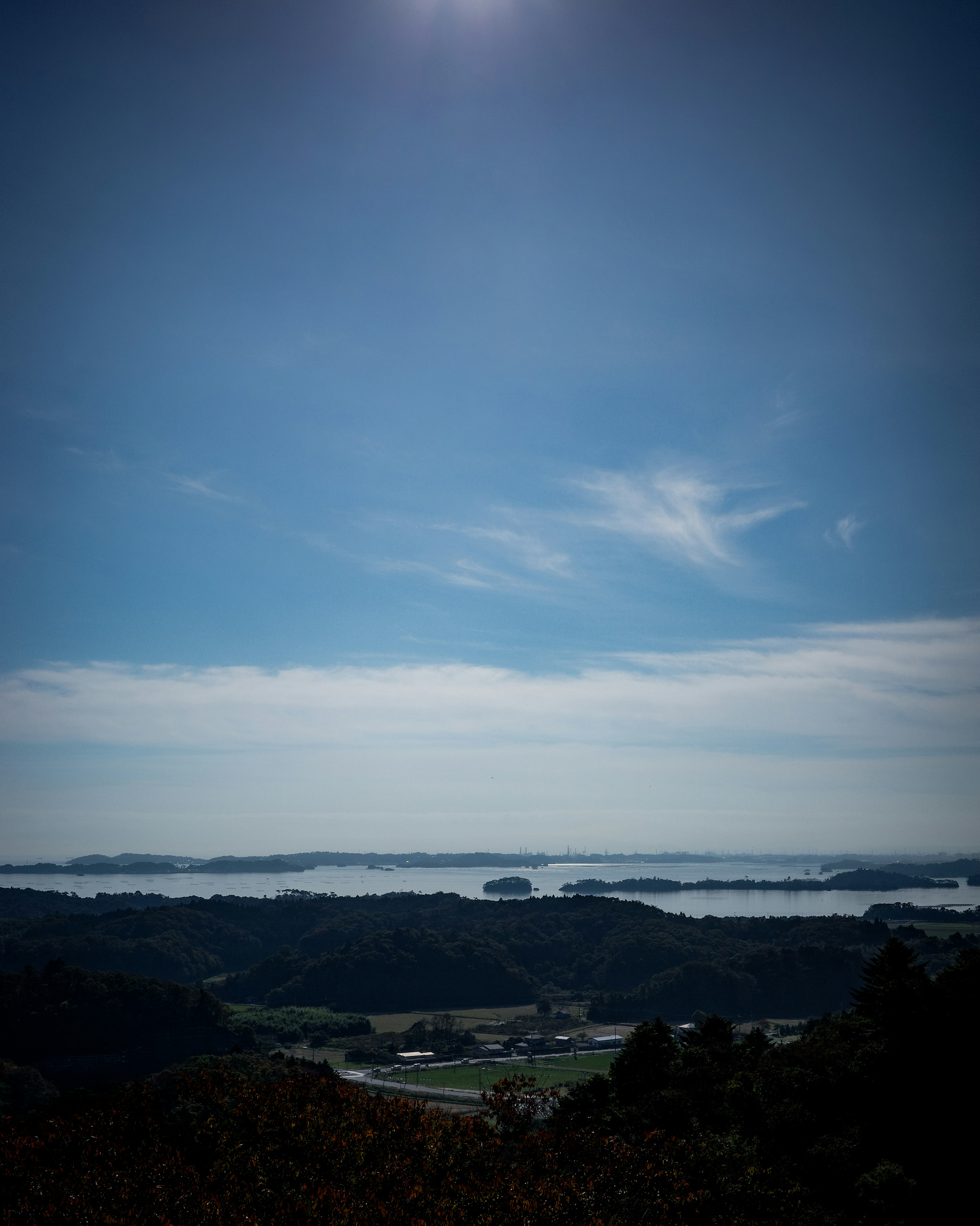 青空と雲が広がる風景 霧に包まれた丘と川が見える