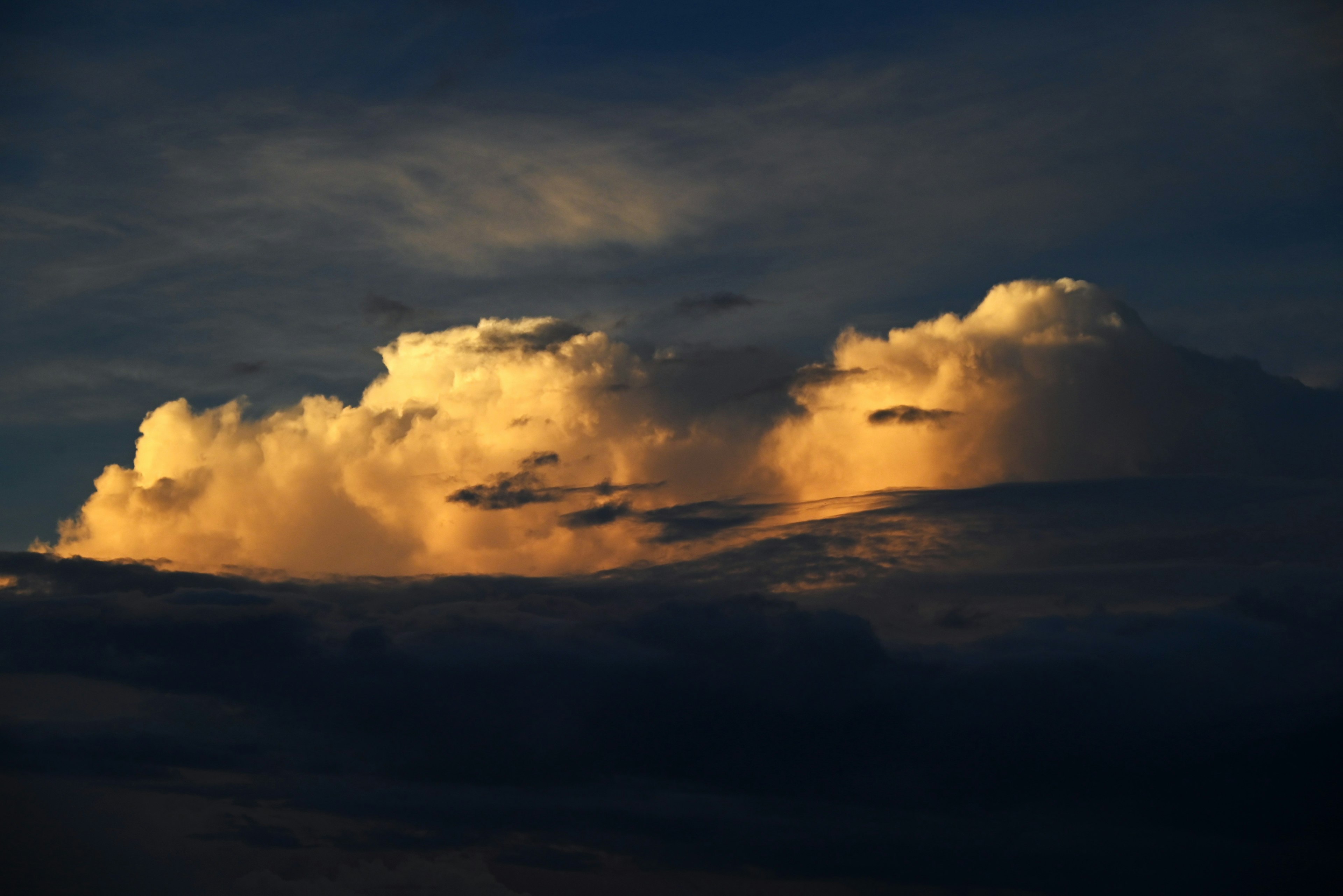 夕暮れ時の雲にオレンジ色の光が当たっている