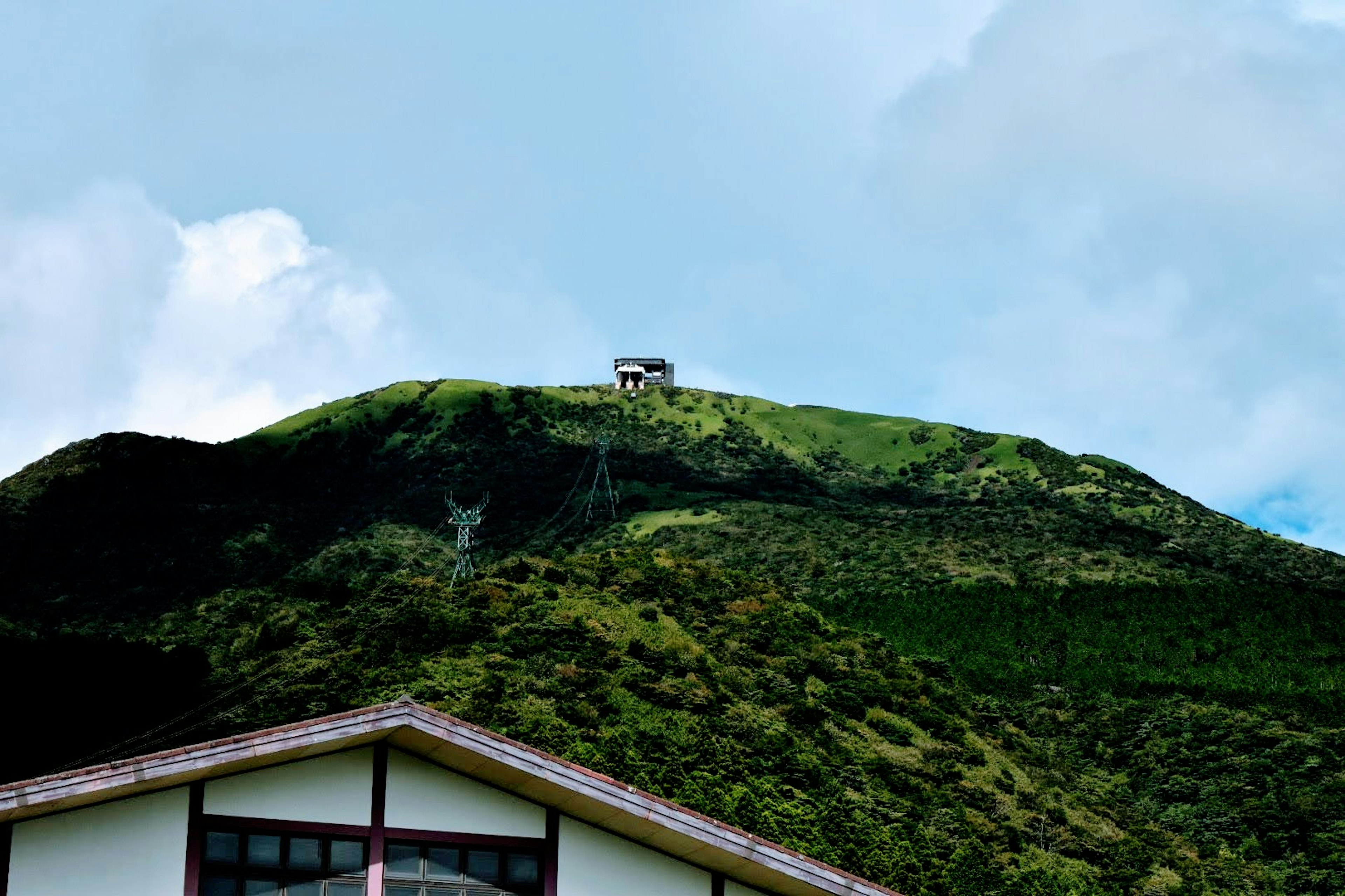 Un piccolo edificio su una collina verde sotto un cielo blu