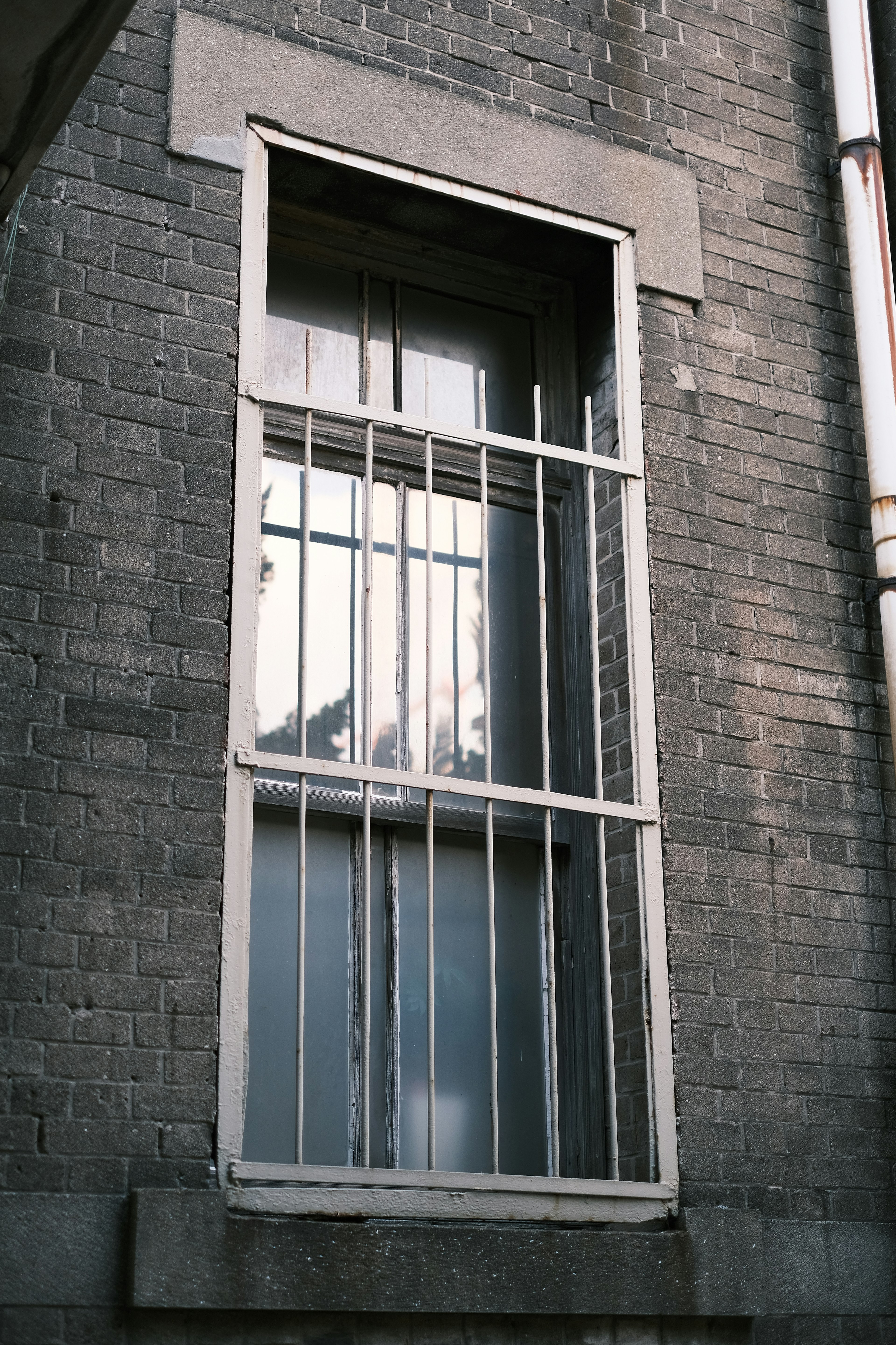 Fenster mit weißen Gitterstäben an einer grauen Ziegelwand