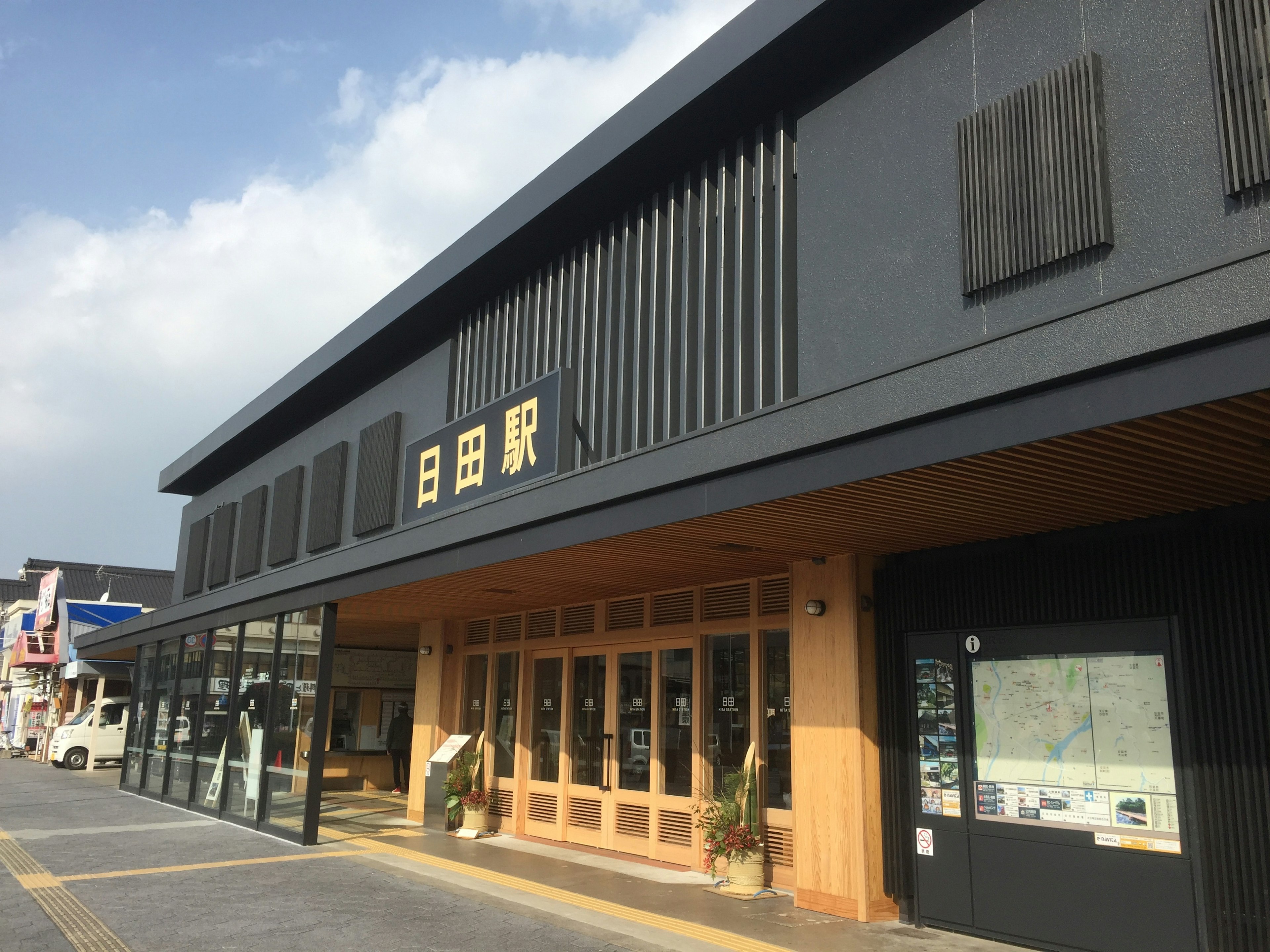 Modern train station exterior featuring black walls and a wooden entrance