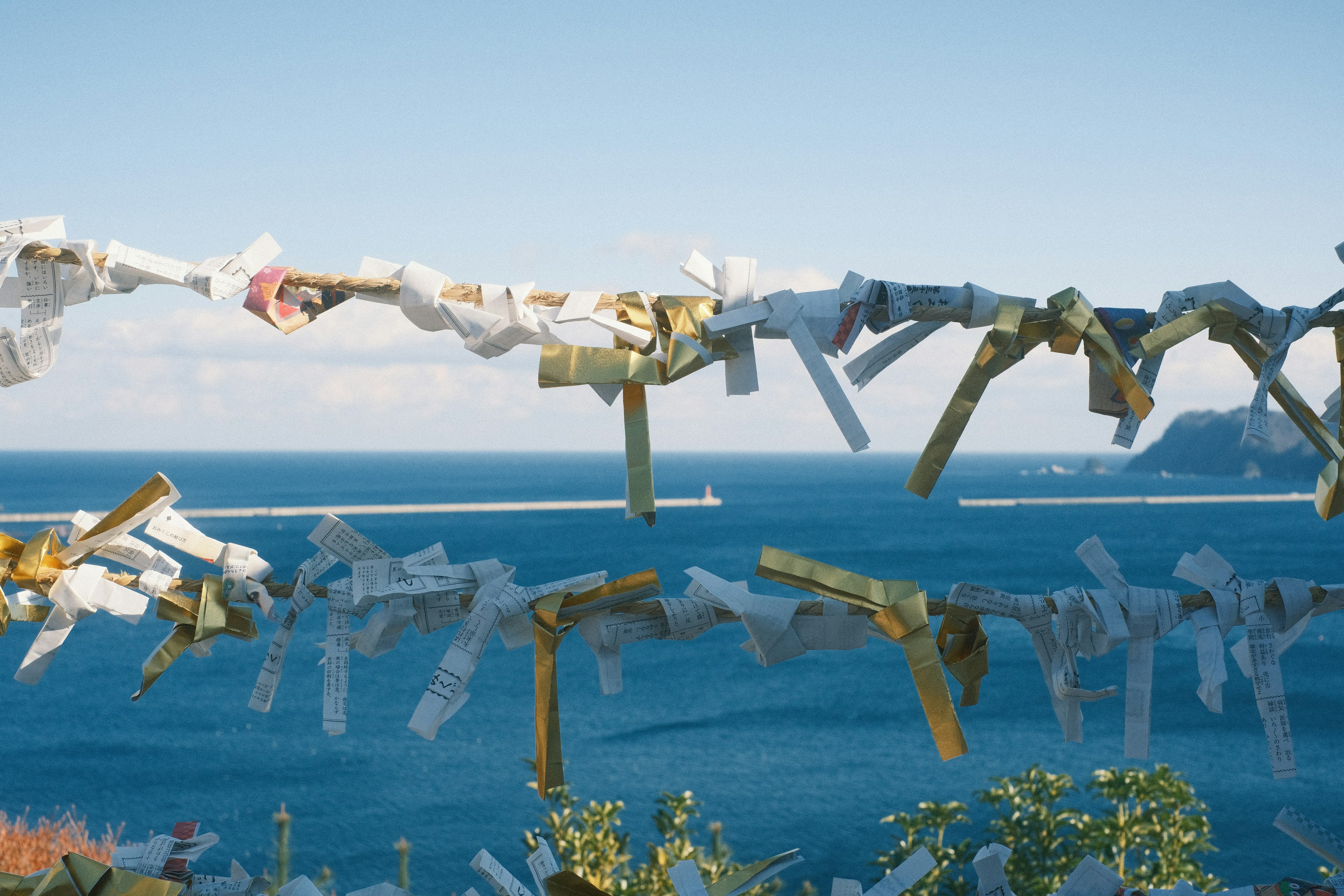 Landschaft mit weißen Papierstreifen, die vor einem blauen Meer hängen