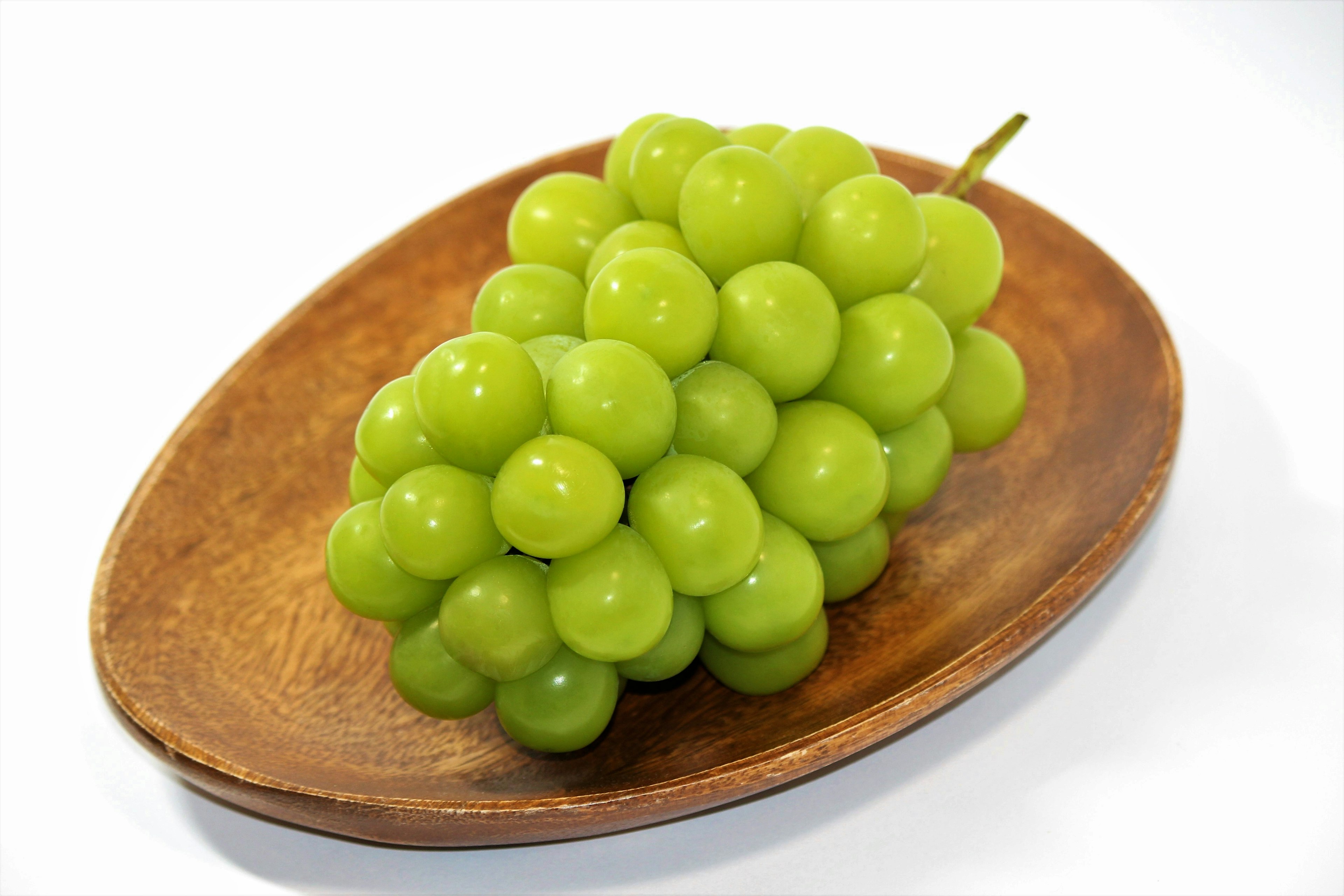 Un racimo de uvas verdes frescas en un plato de madera