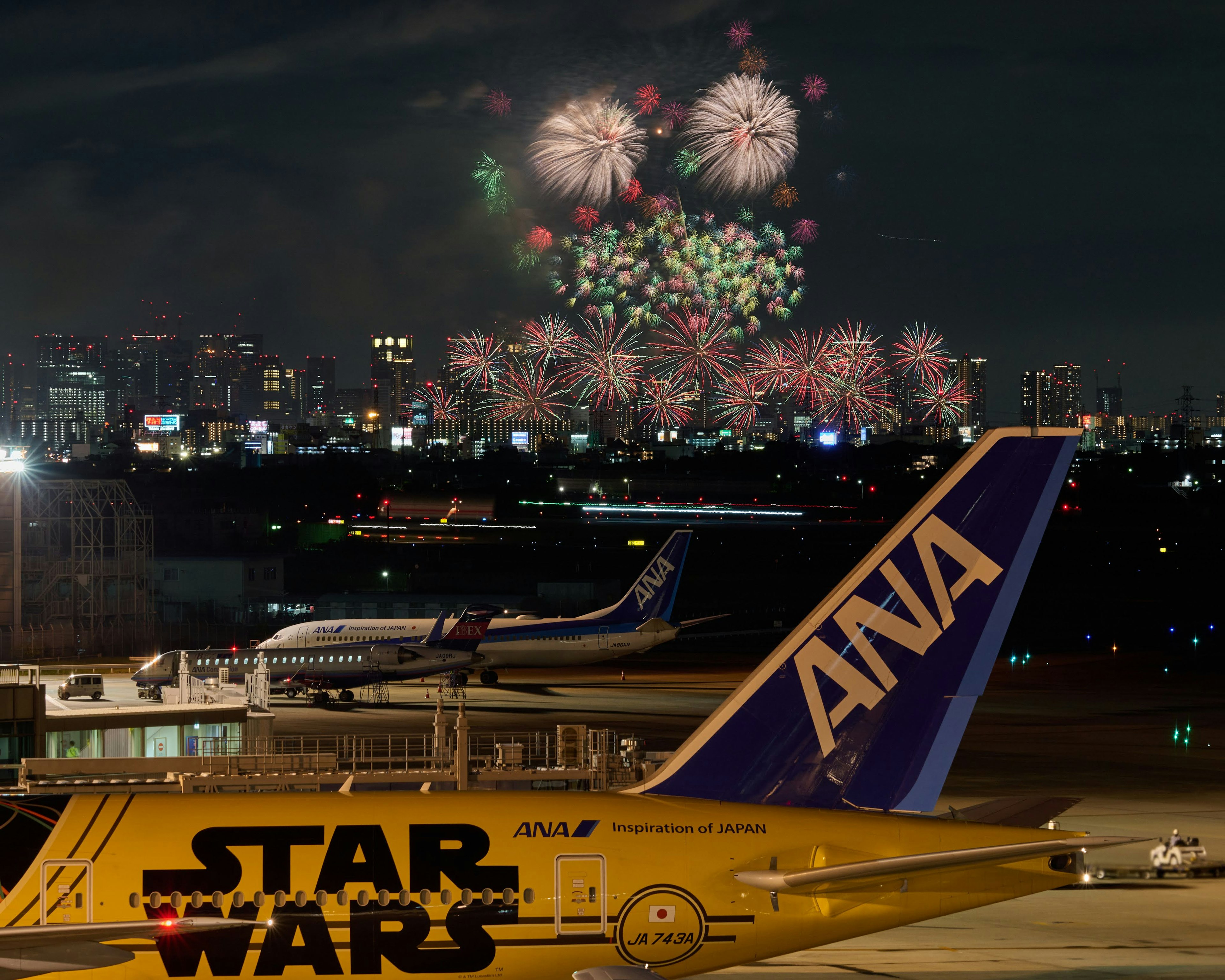 Avion ANA avec des feux d'artifice dans le ciel nocturne