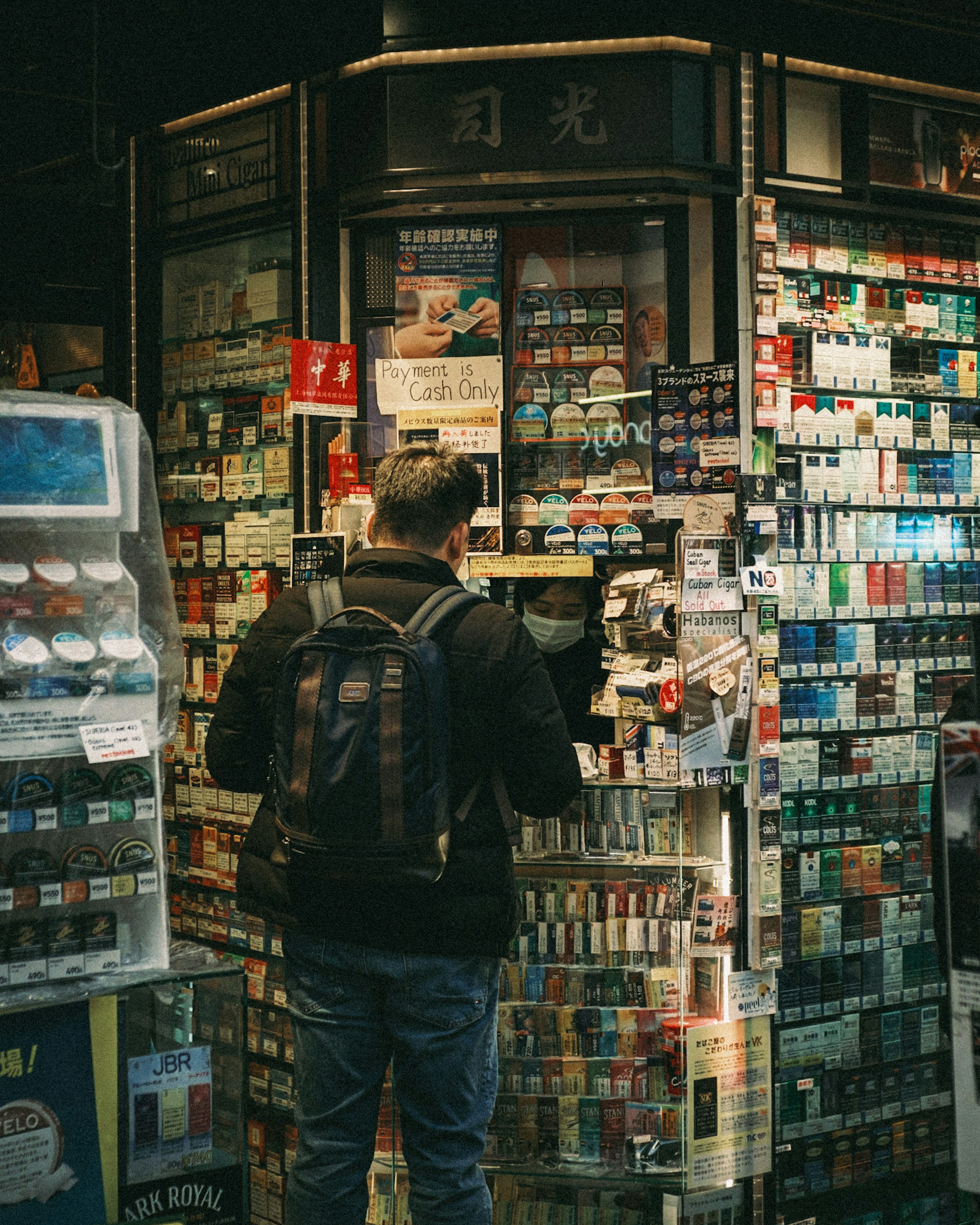 Homme se tenant devant une machine à cigarettes