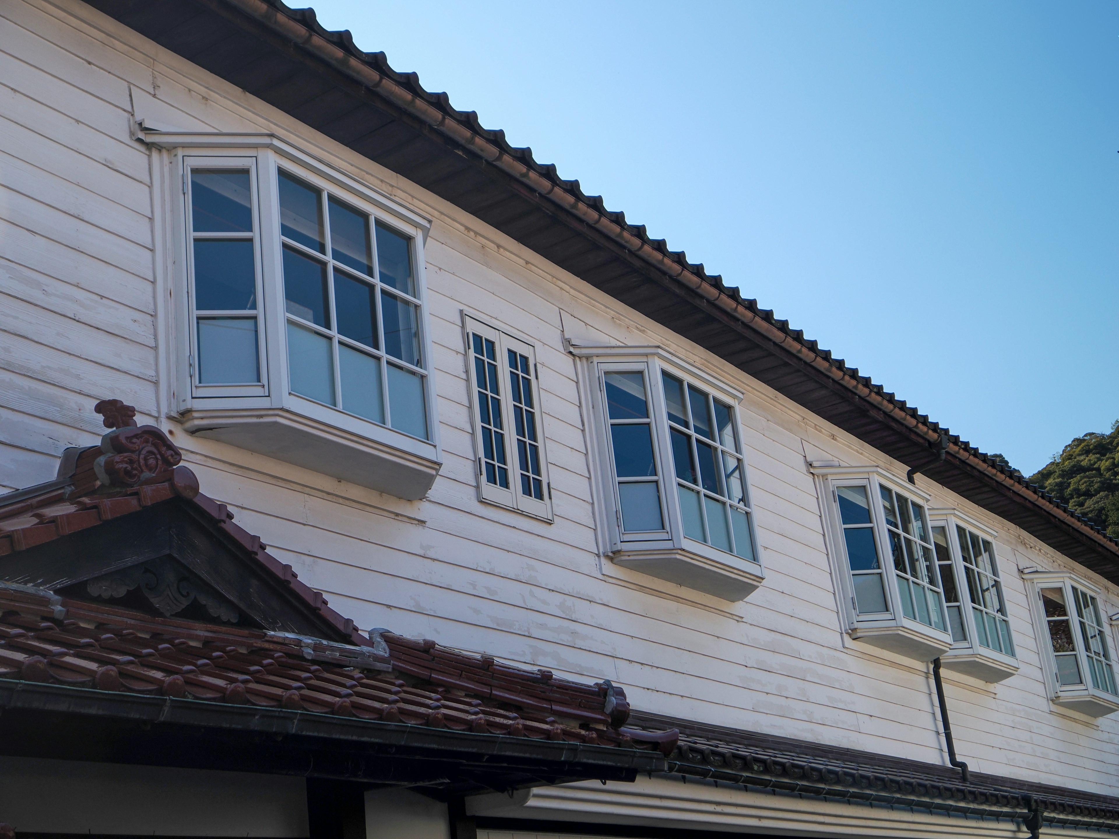 Mehrere Fenster an einem weißen Haus mit klarem blauen Himmel