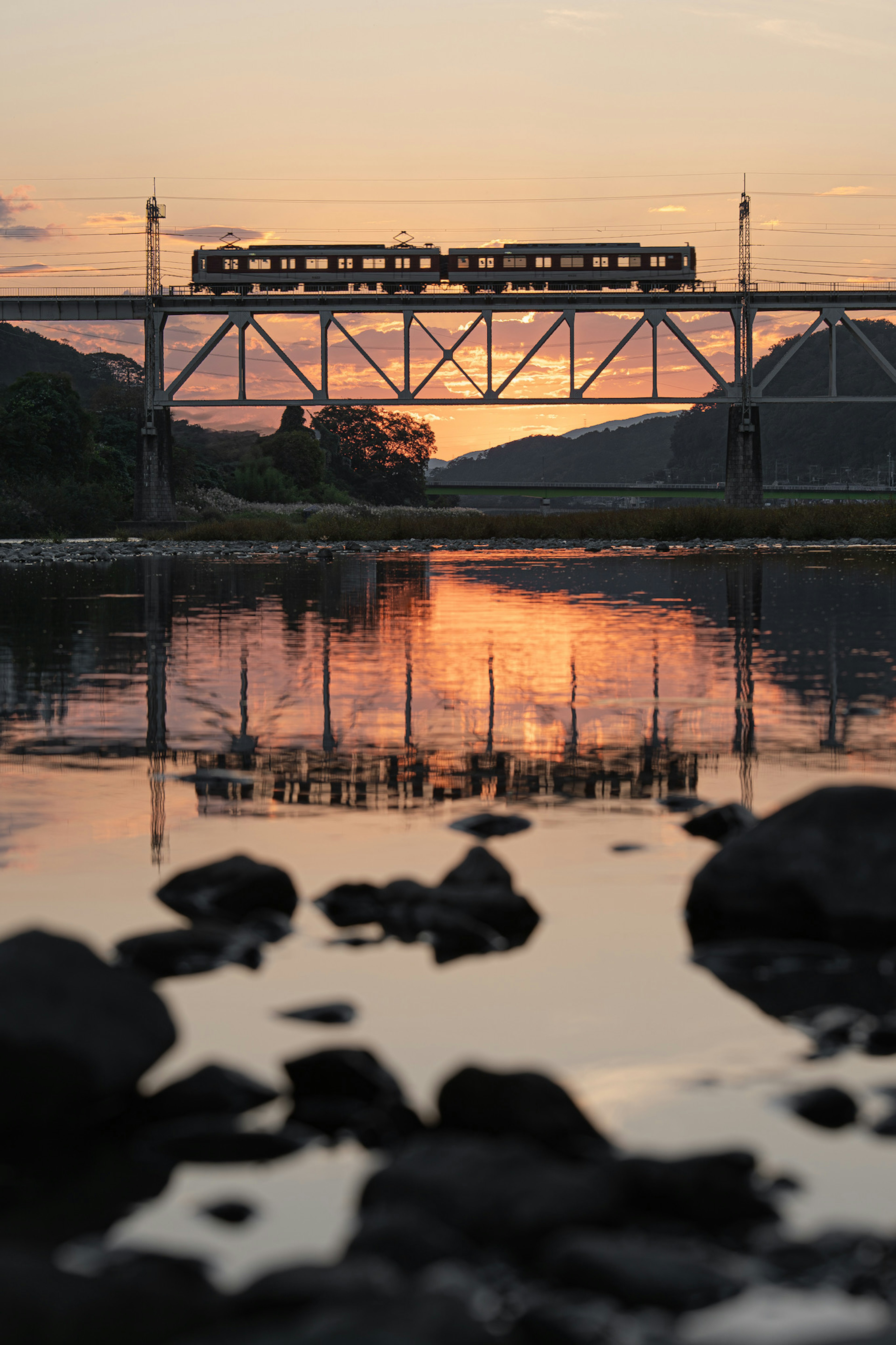 ทิวทัศน์สวยงามของสะพานรถไฟสะท้อนในแม่น้ำขณะพระอาทิตย์ตก