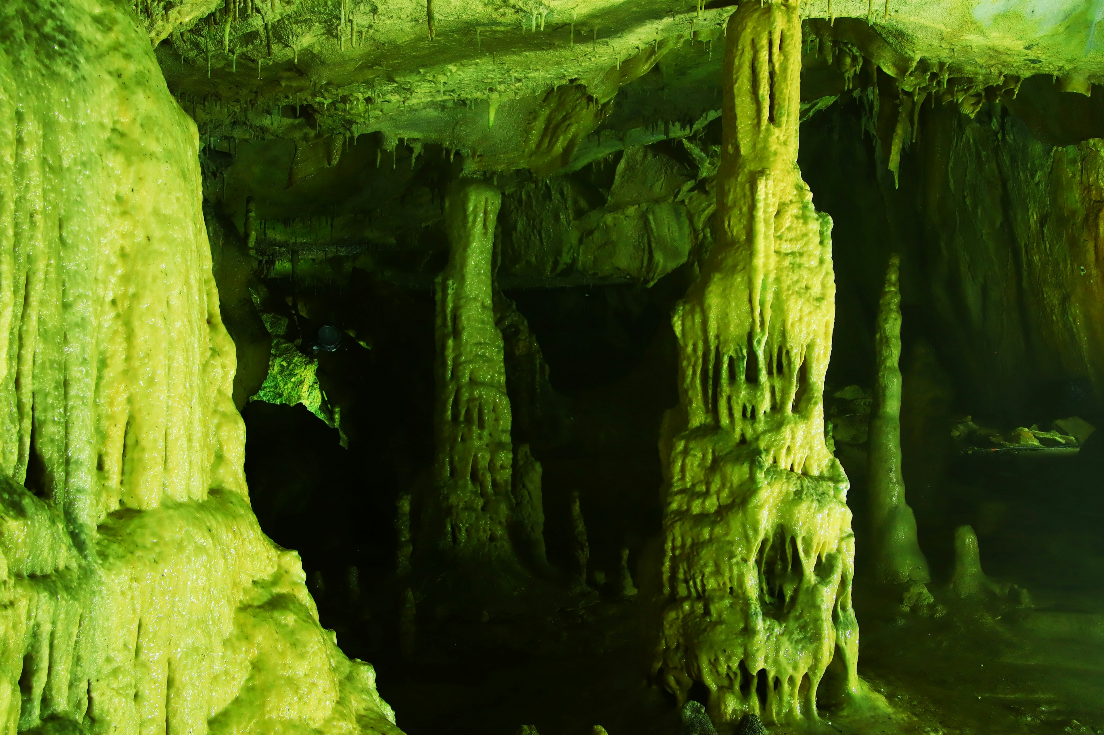 Vista interna di una grotta con stalattiti e stalagmiti verdi