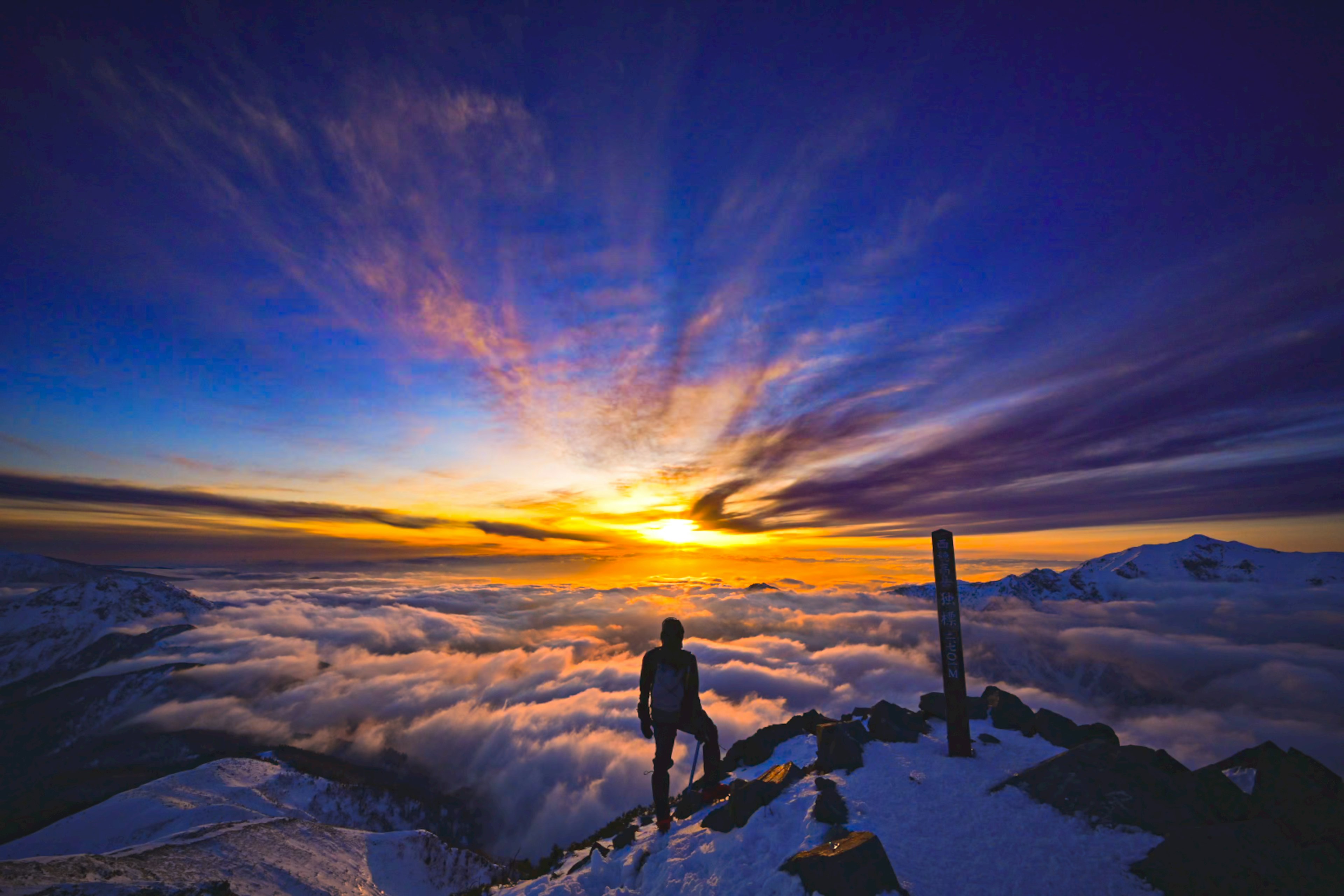 Stunning sunset view from a snowy mountain peak with a sea of clouds