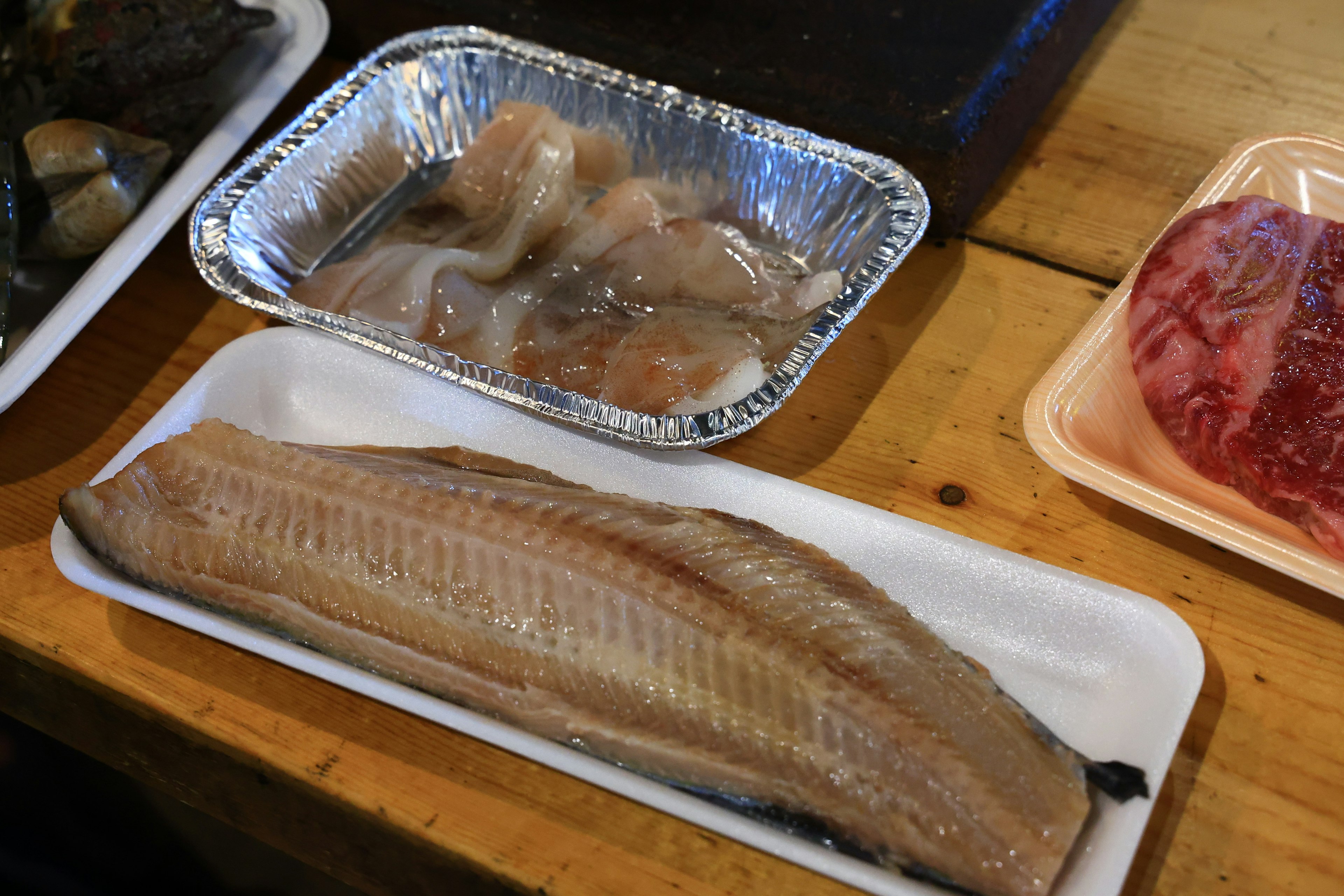 Un plato con filete de pescado y mariscos sobre una mesa de madera