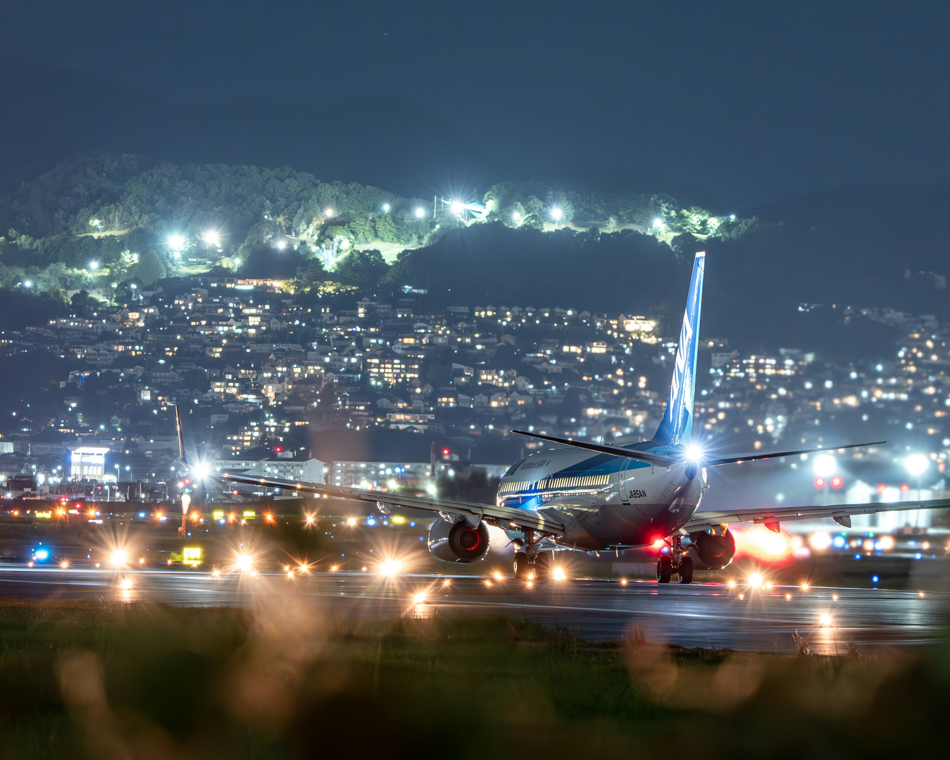 Flugzeug auf der Landebahn bei Nacht mit Stadtlichtern im Hintergrund