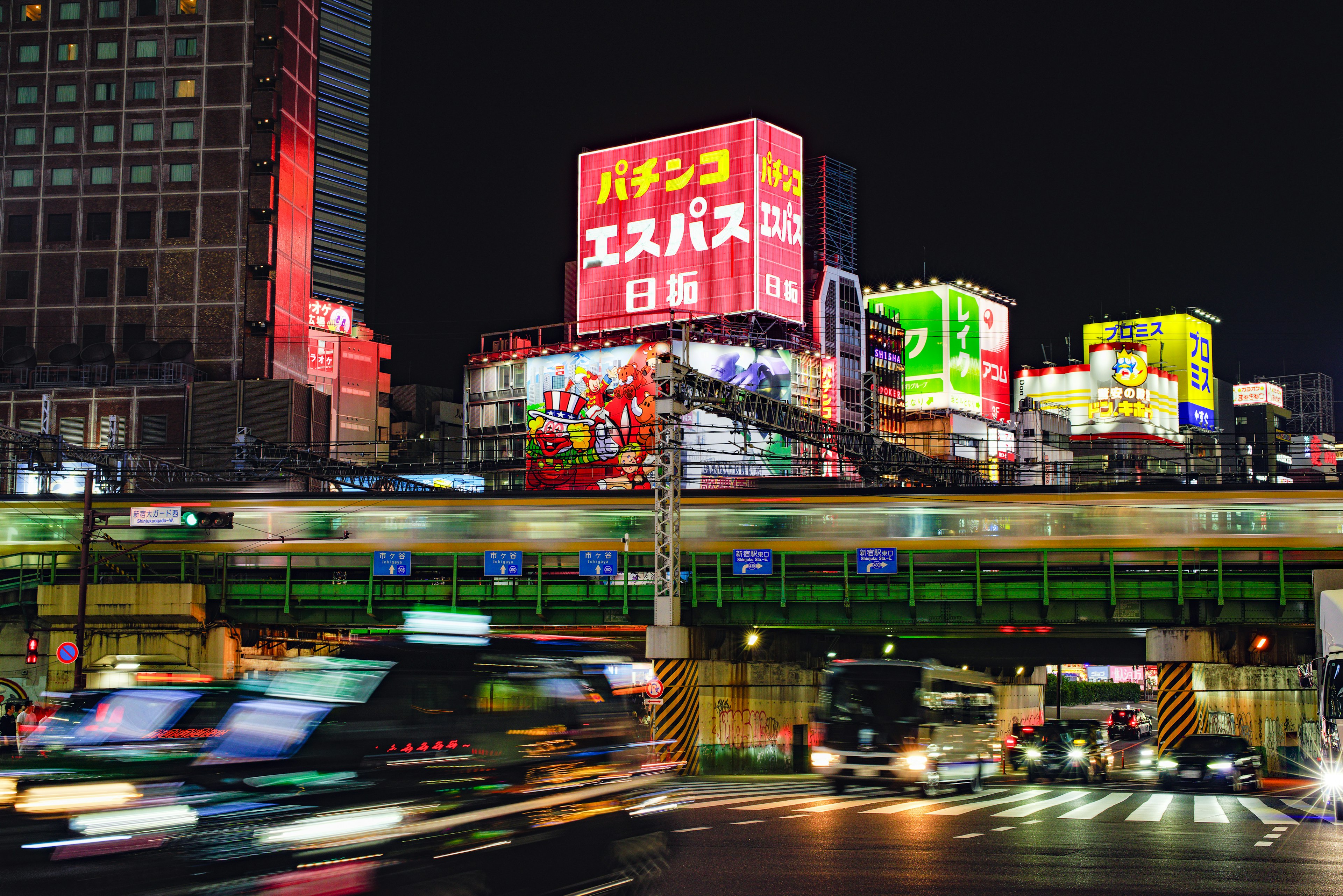 Vibrant night cityscape featuring neon signs and a train