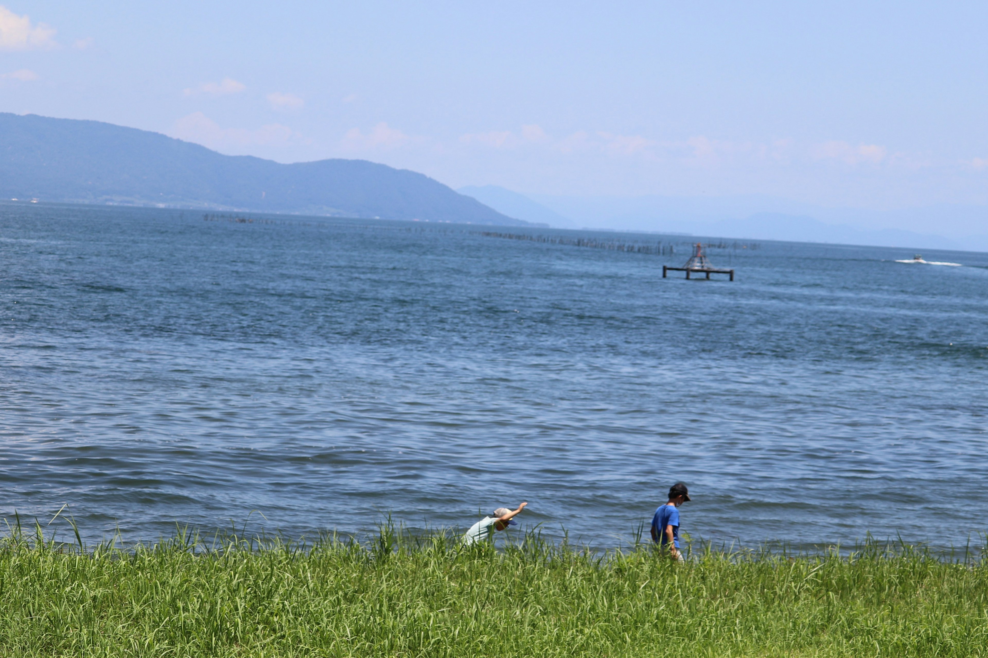 Enfants jouant au bord de la mer bleue avec des montagnes en arrière-plan