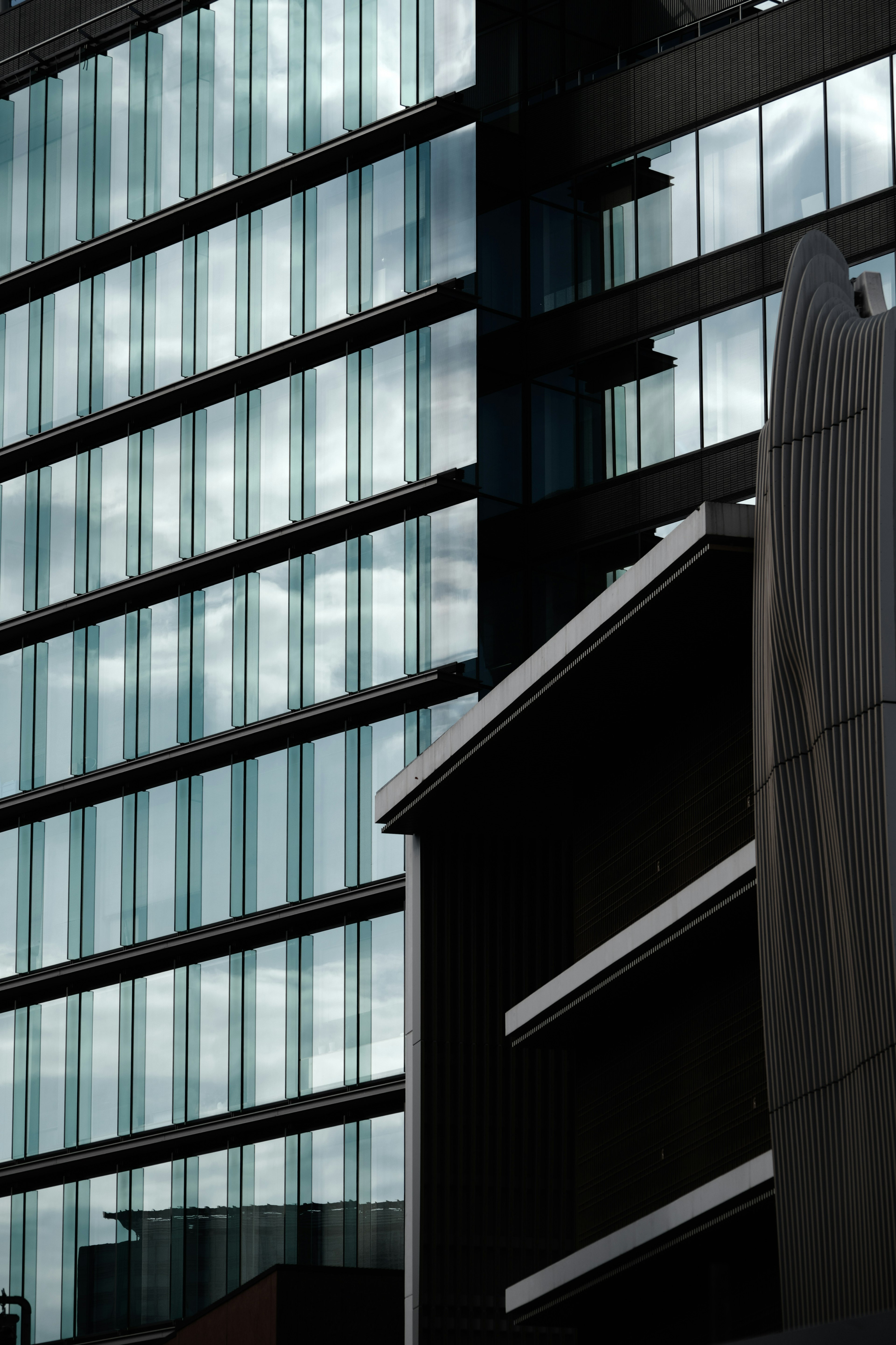 Façade en verre moderne d'un bâtiment contrastant avec des structures adjacentes