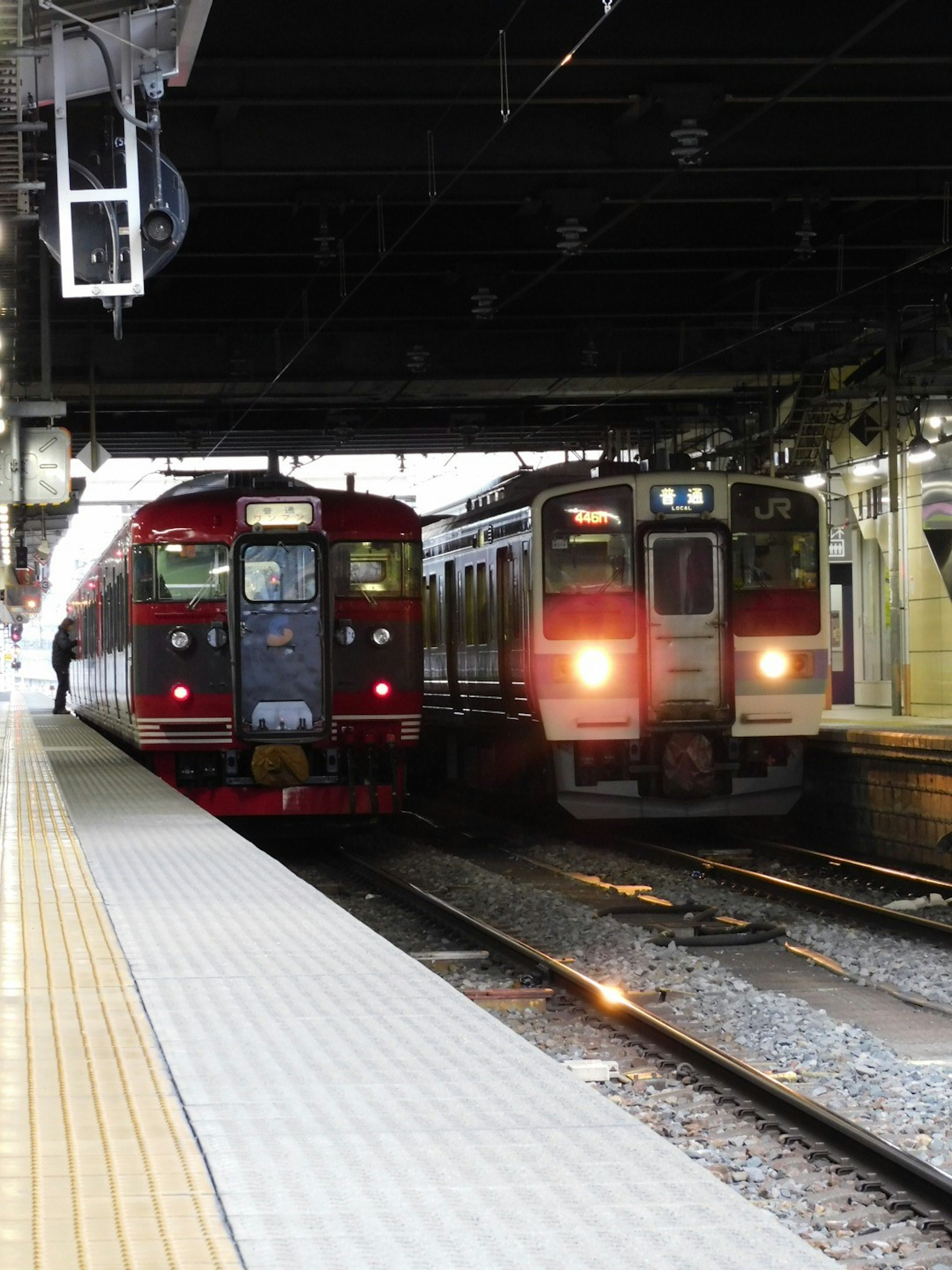 赤い電車と白い電車が駅のプラットフォームで交差する風景