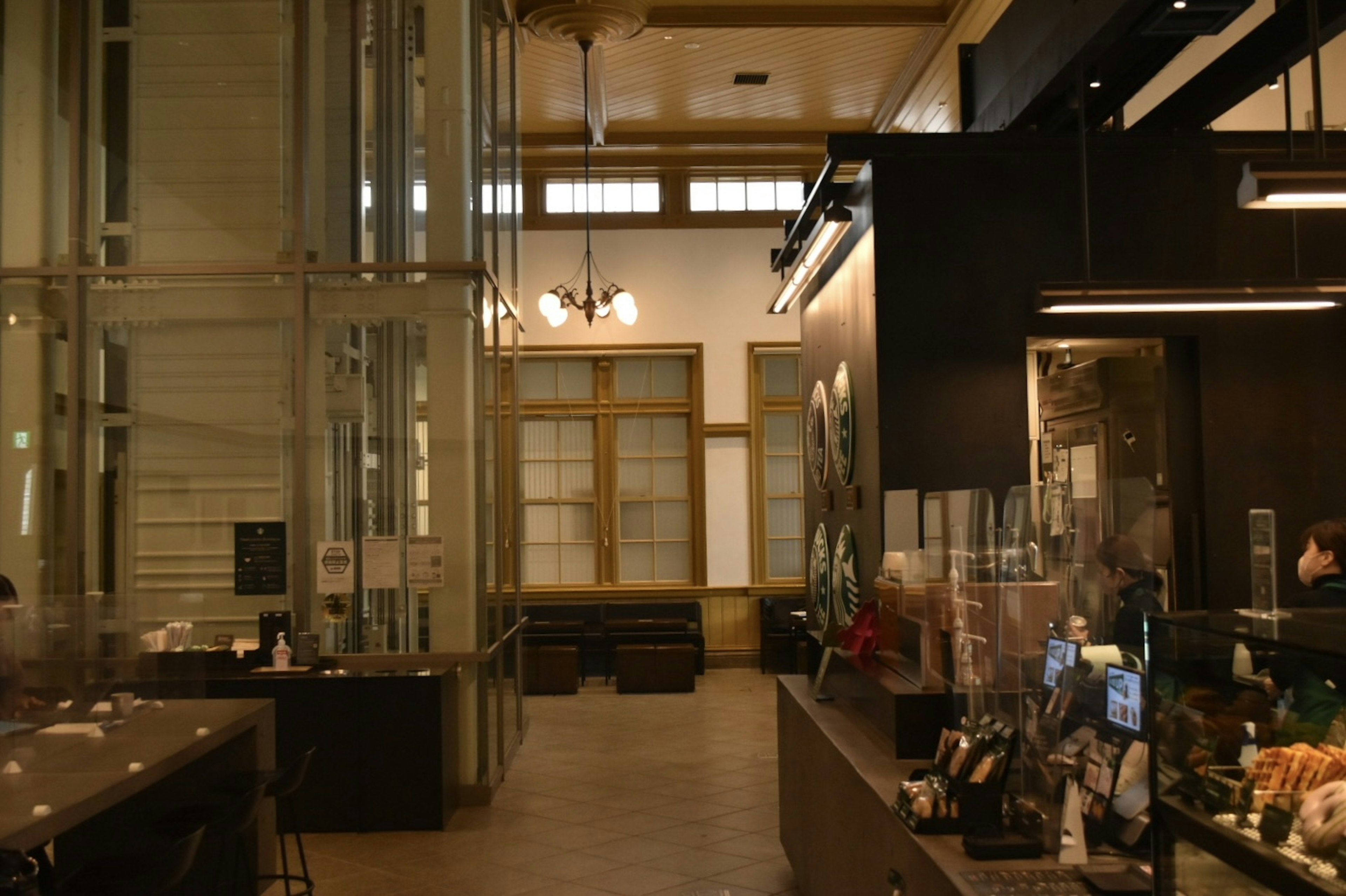 Interior de una cafetería moderna con paredes de vidrio y ventanas de madera