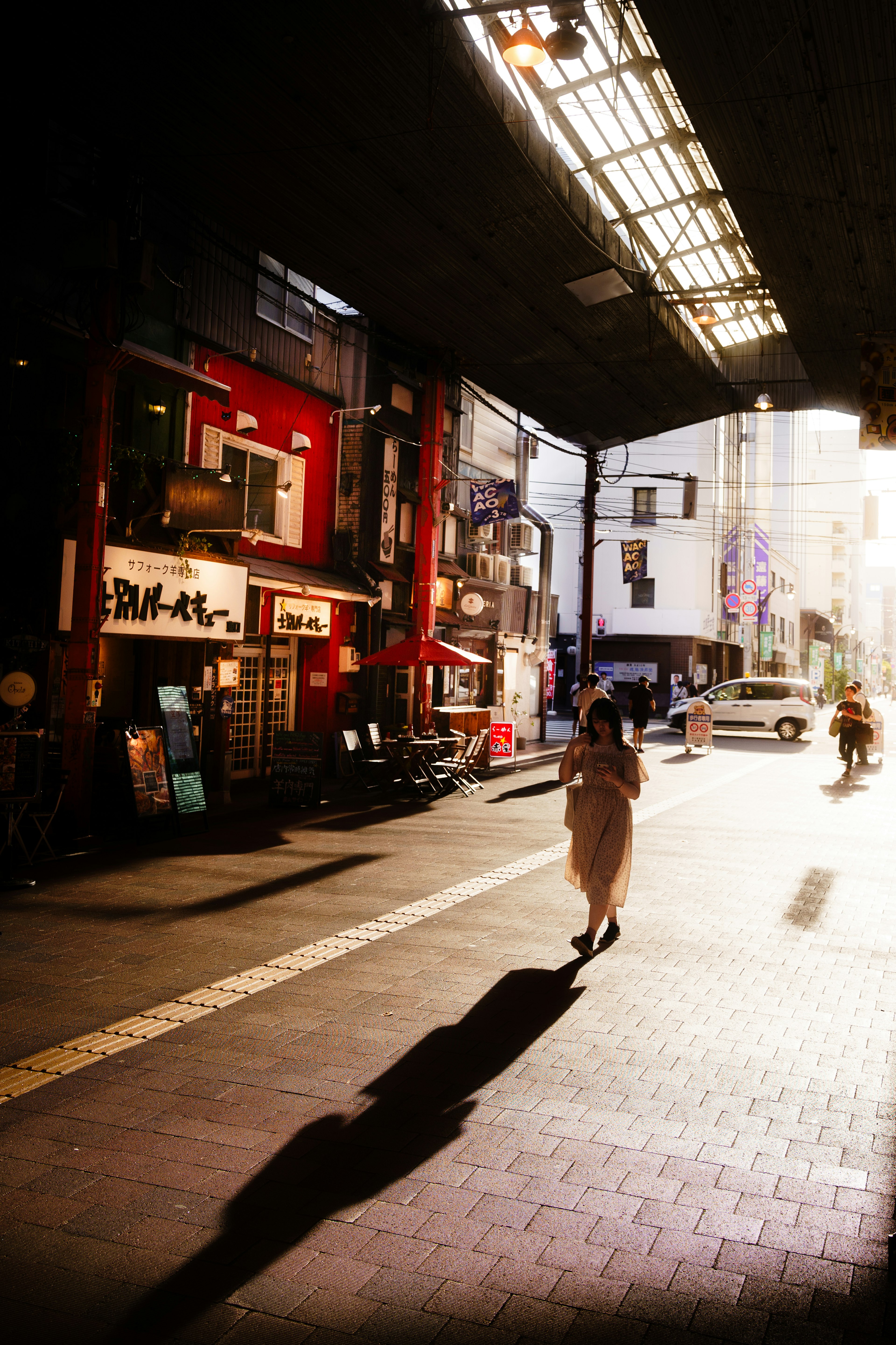 Silhouette d'une femme marchant dans une rue en soirée avec des magasins