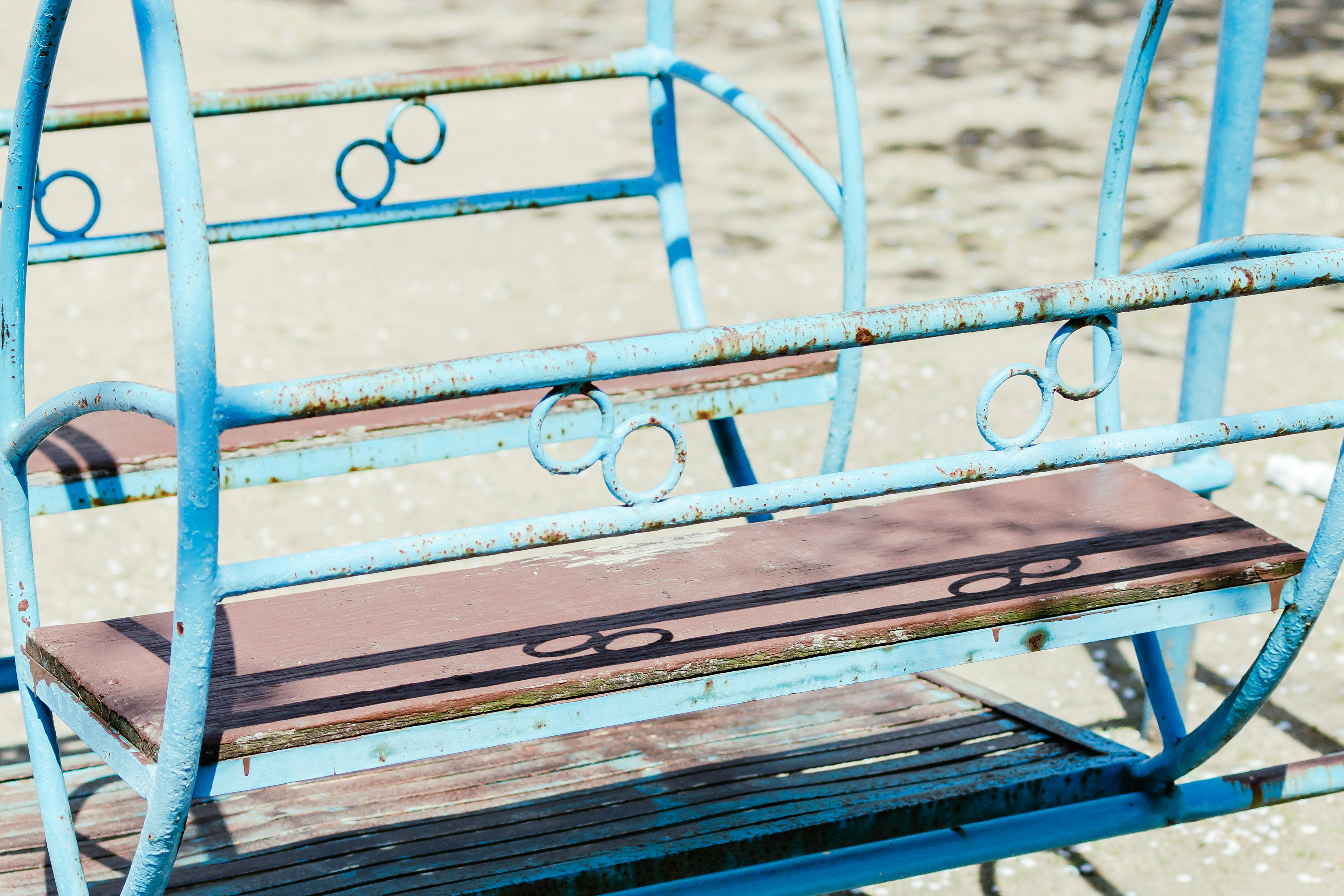 Acercamiento a un banco de metal azul con un asiento de madera marrón