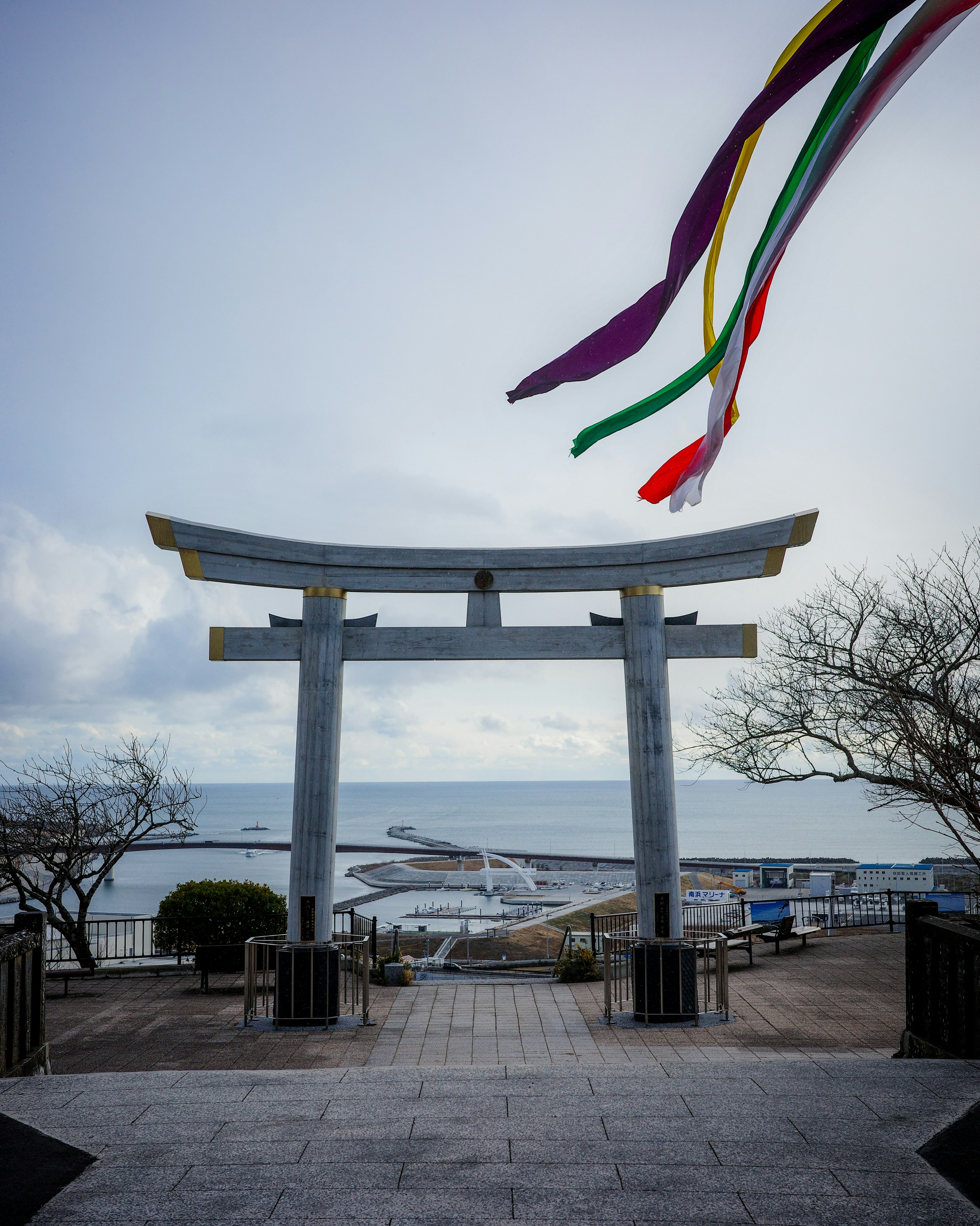 青い海を背景にした鳥居と色とりどりの吹き流し